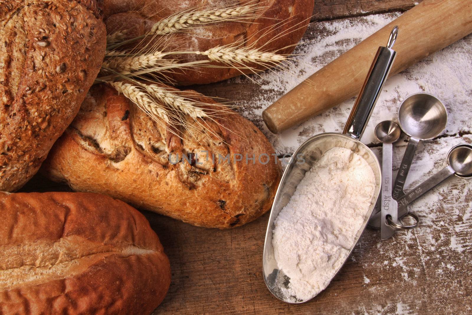 Assortment of loaves of bread with flour on wood table