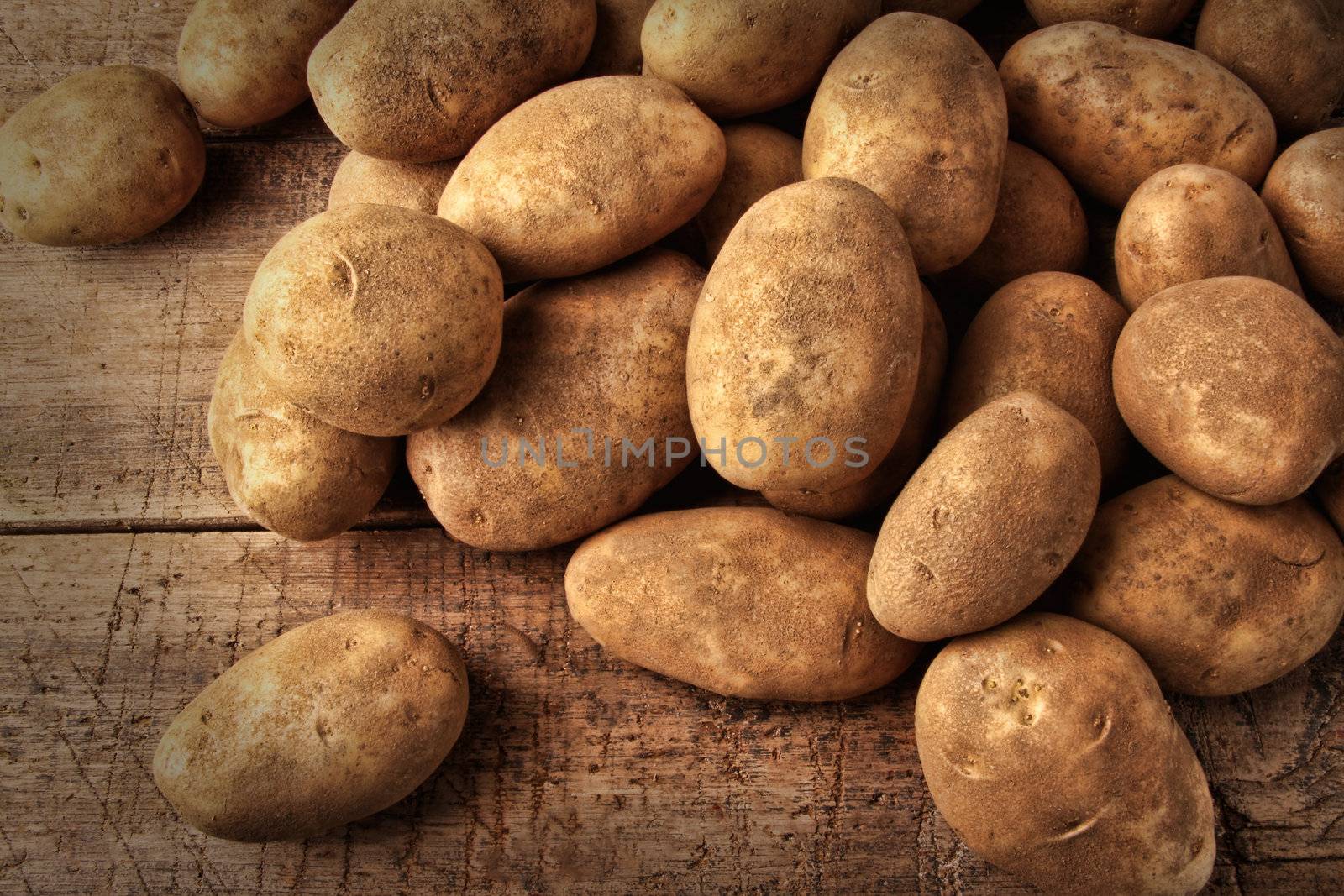 Fresh potatoes on wooden background  by Sandralise