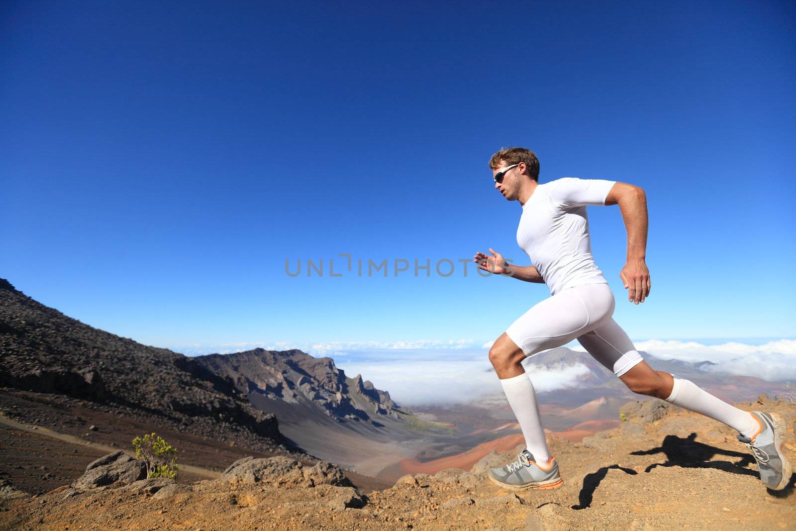 Running sport. Man runner sprinting outdoor in scenic nature. Fit muscular male athlete training trail running for marathon run. Sporty fit athletic man working out in compression clothing doing sprint.