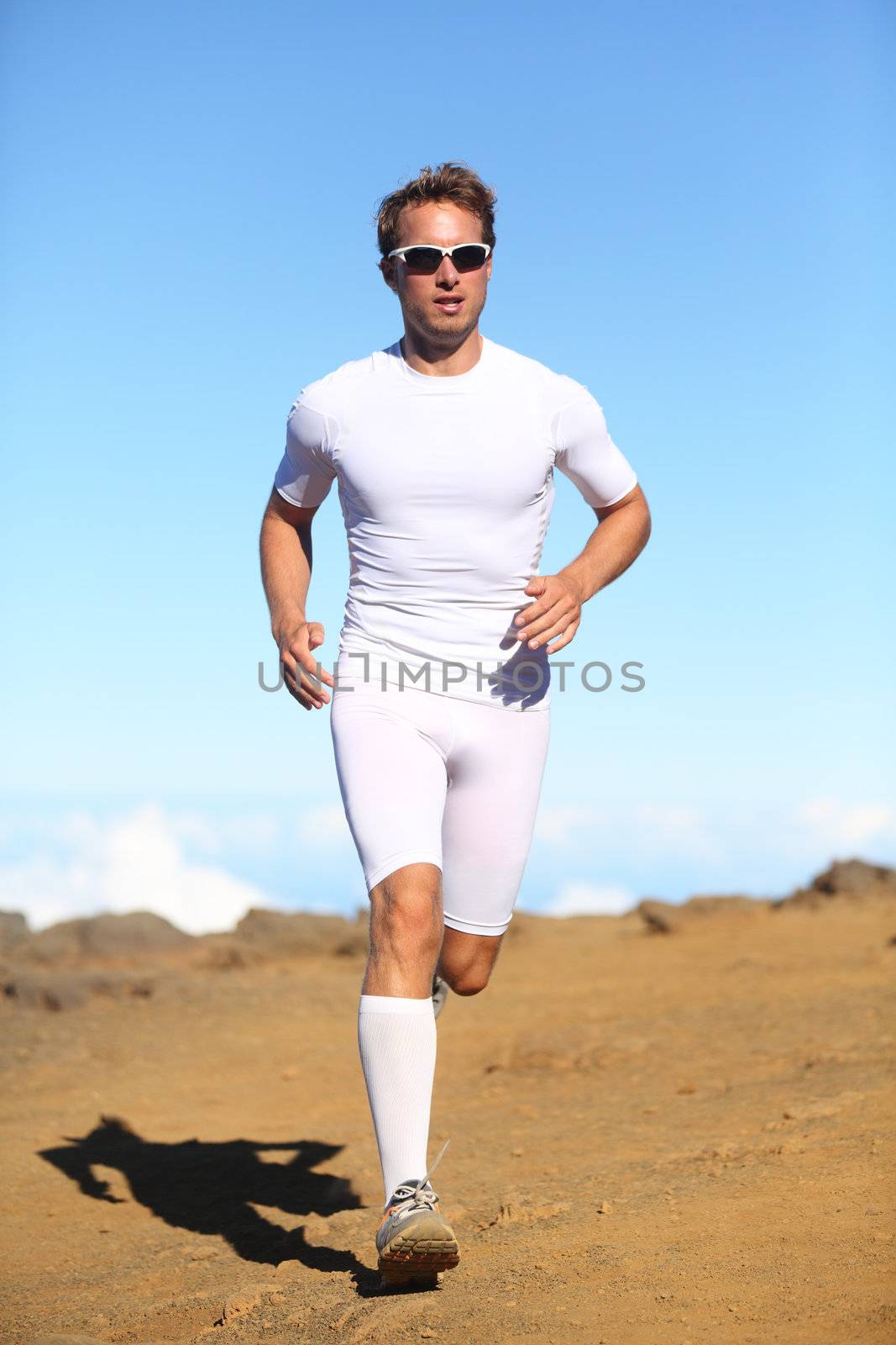 Athlete sports fitness runner running outside in nature. Man training trail running in beautiful scenery for marathon run. Sporty fit athletic male working out in compression clothing.