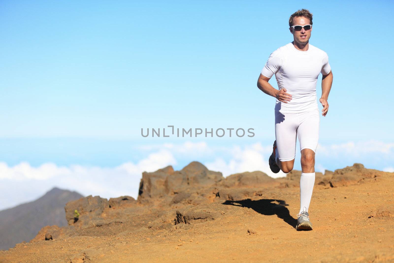 Runner man trail running in scenic landscape nature in compression clothing. Young fit male fitness athlete training outdoor for marathon.