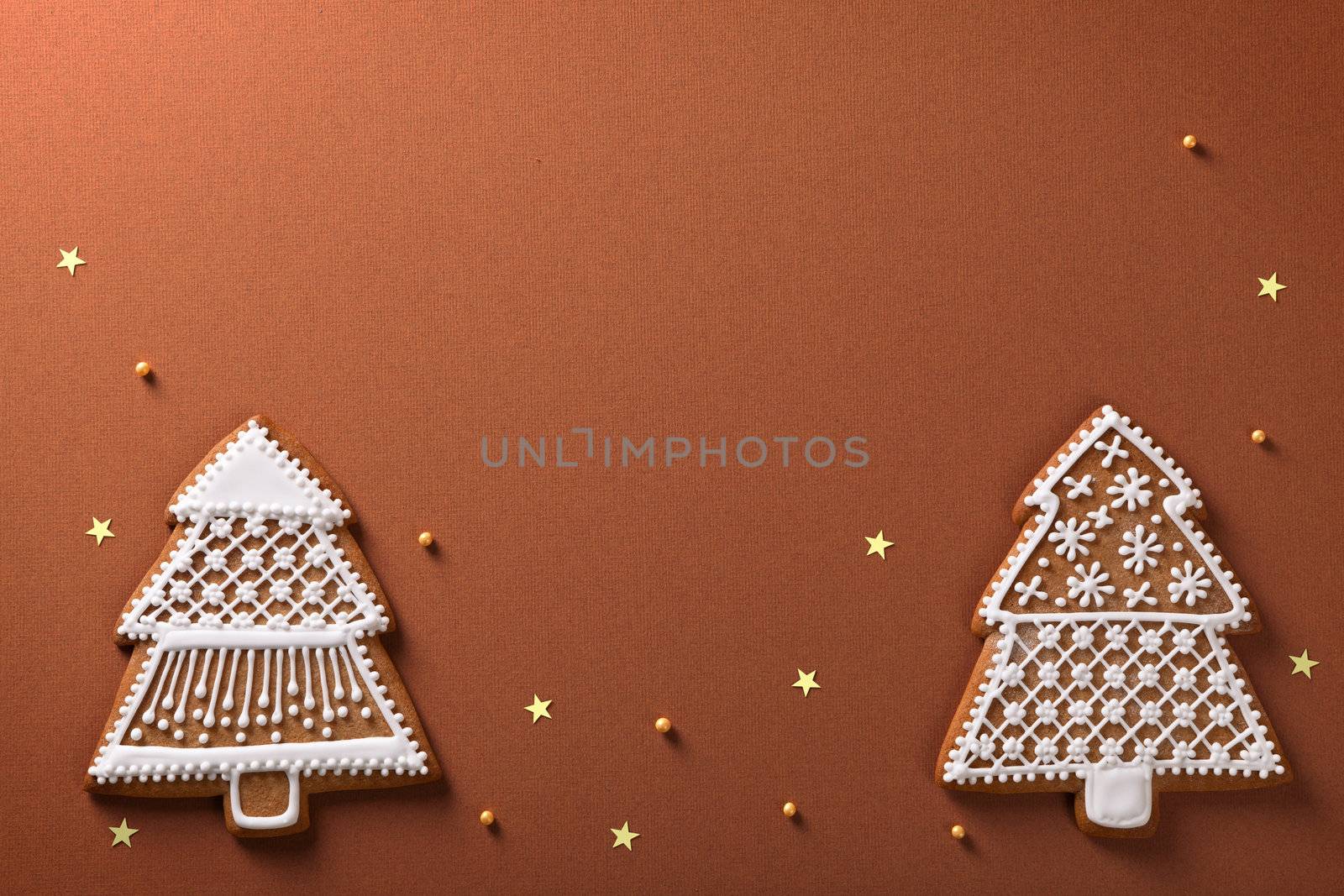 Christmas gingerbread trees composition with golden stars and balls on brown paper background
