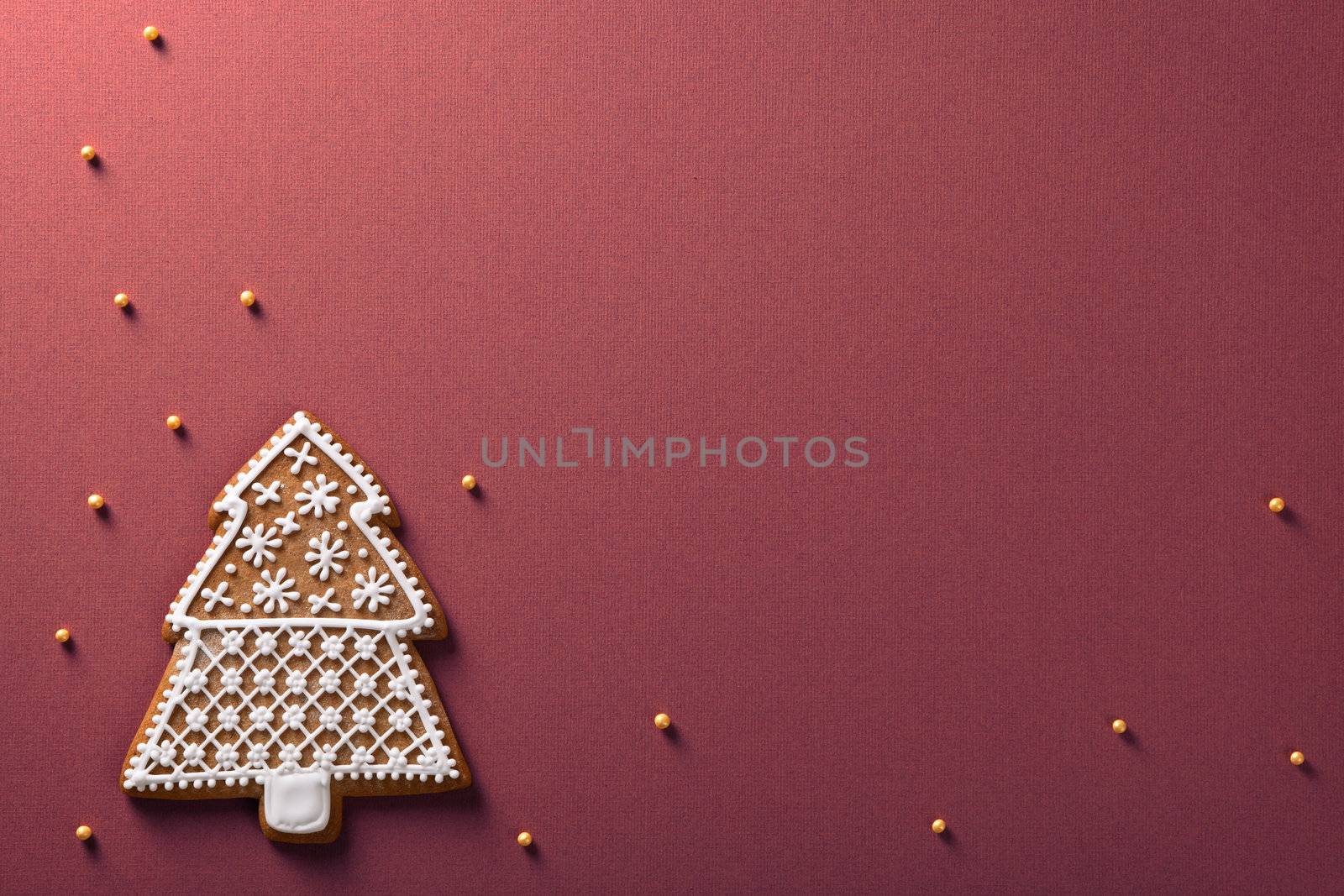 Christmas tree gingerbread with golden balls on violet paper background