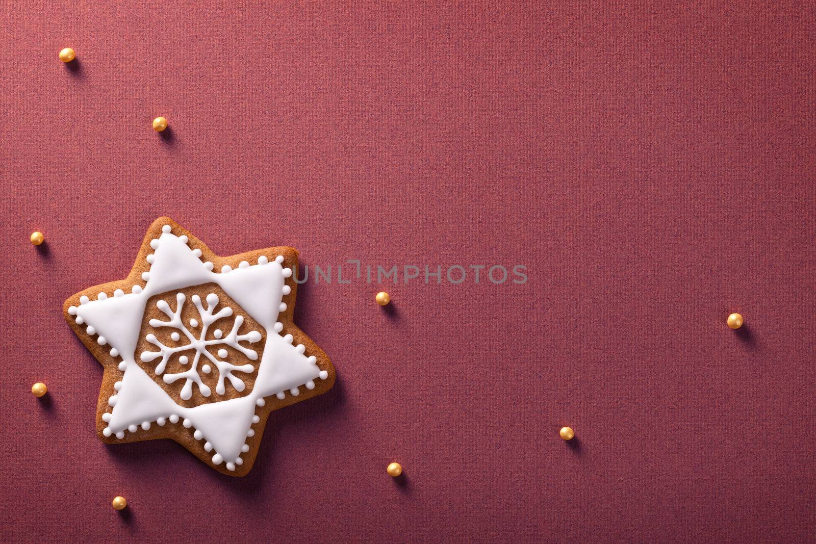 Christmas star gingerbread with golden balls on violet paper background