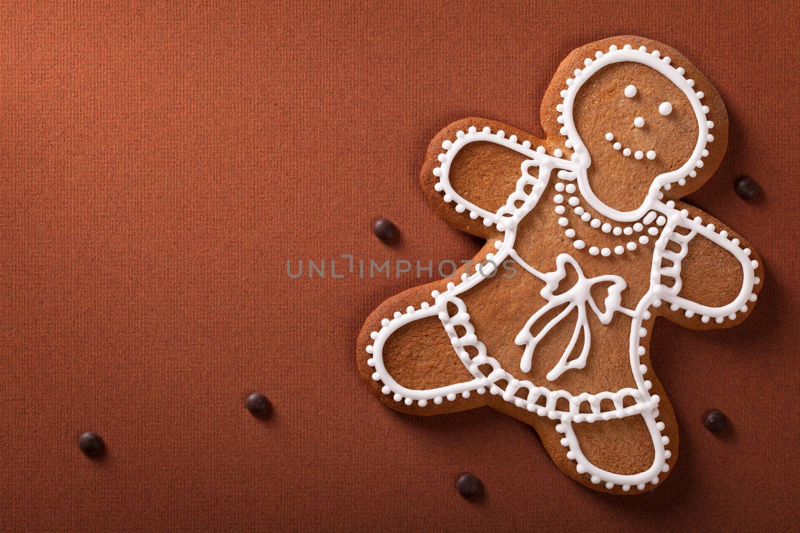 Christmas gingerbread woman with chocolate pills on brown paper background