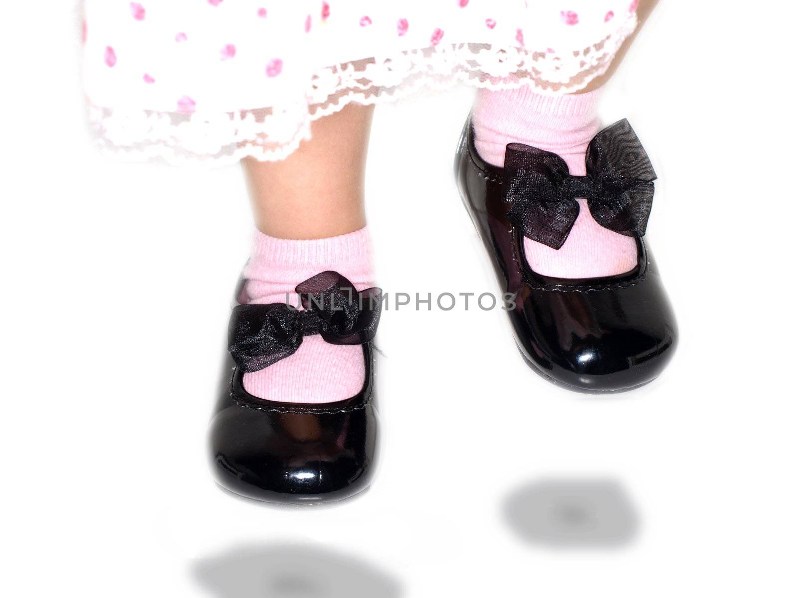 Girl in cute dress, jumping high with shiny black shoes towards white by Arvebettum