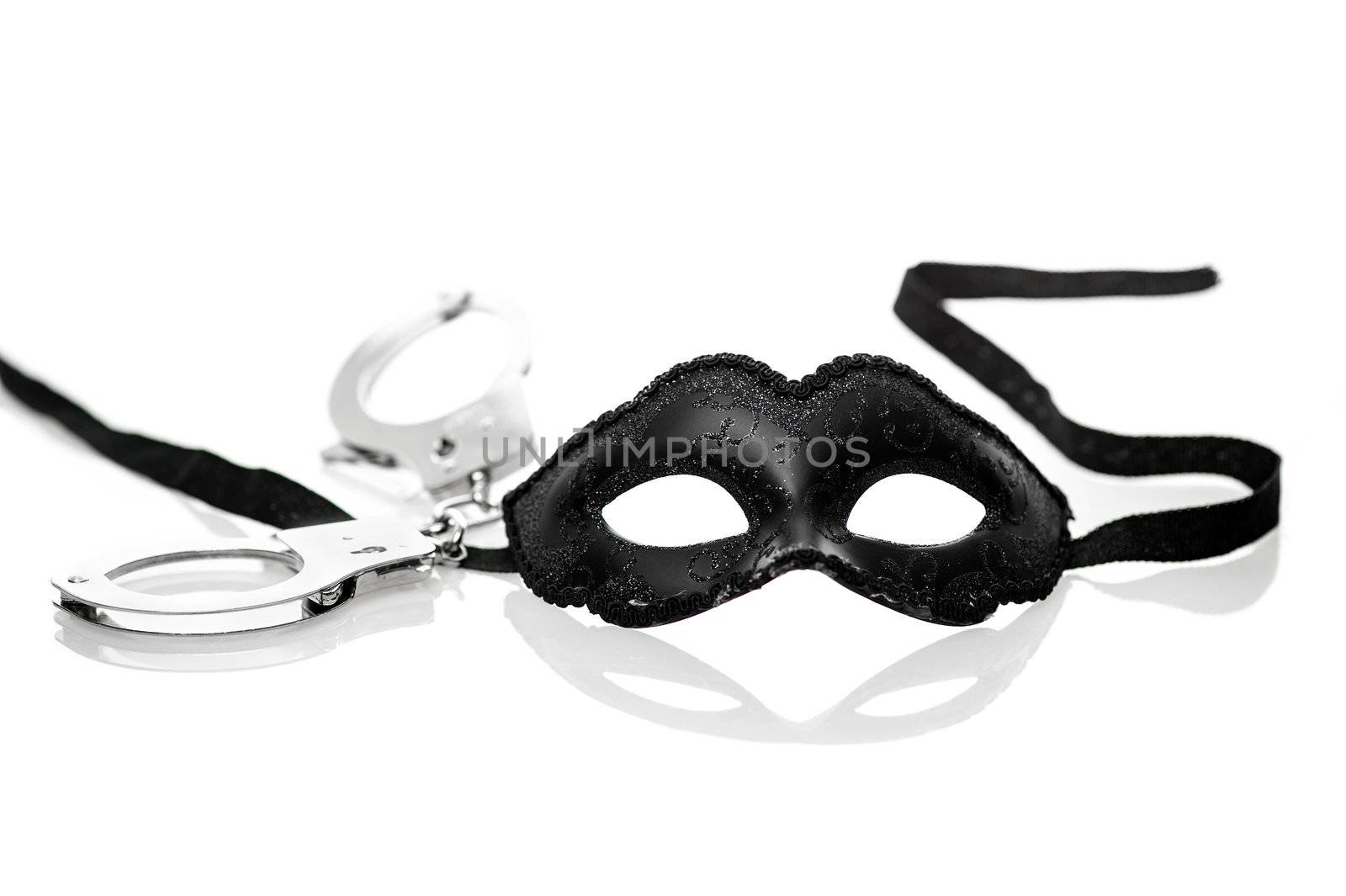 Black mask and handcuffs on white background