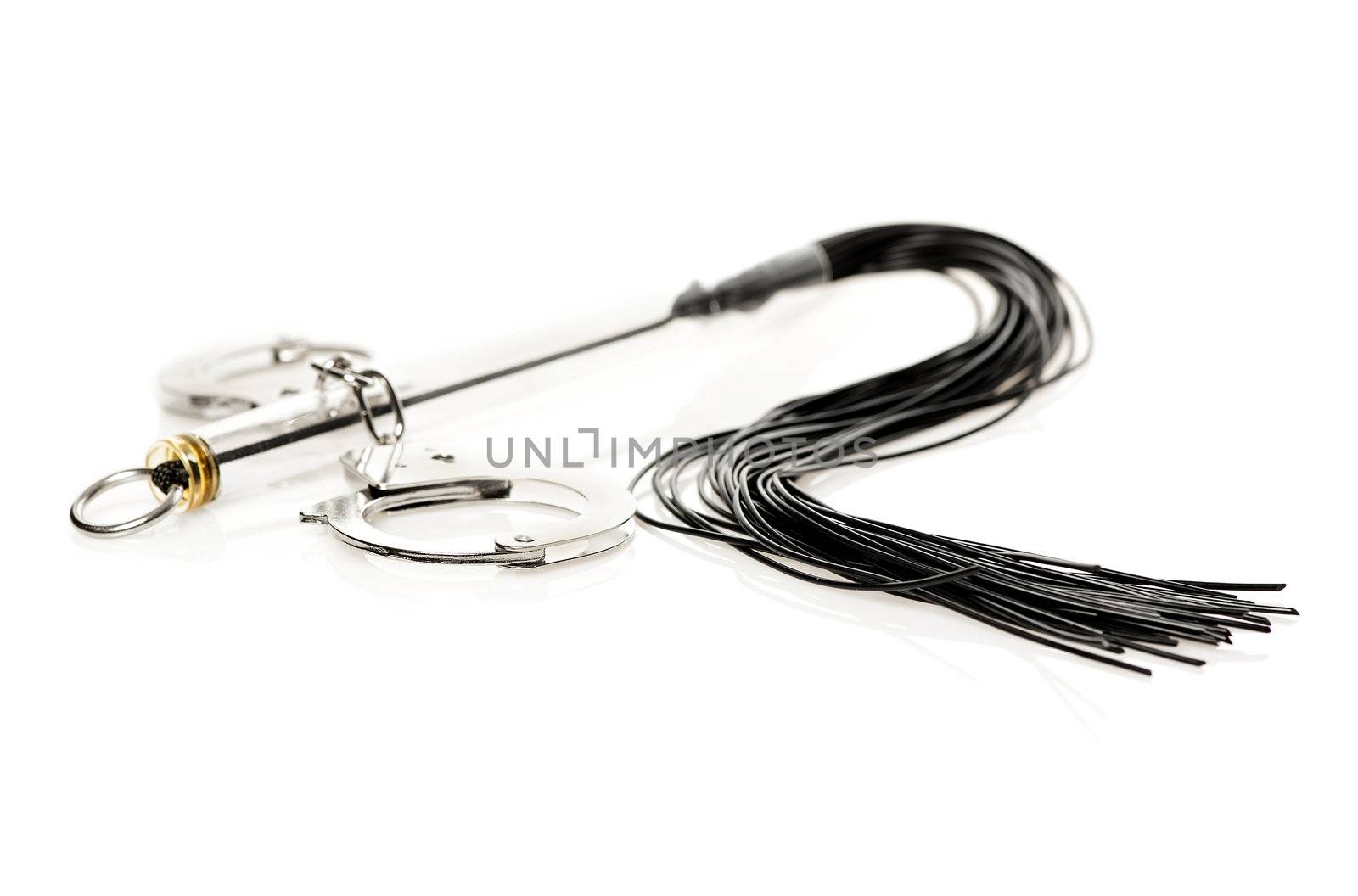 A whip and hand cuffs for fetish/bdsm games isolated on white. 