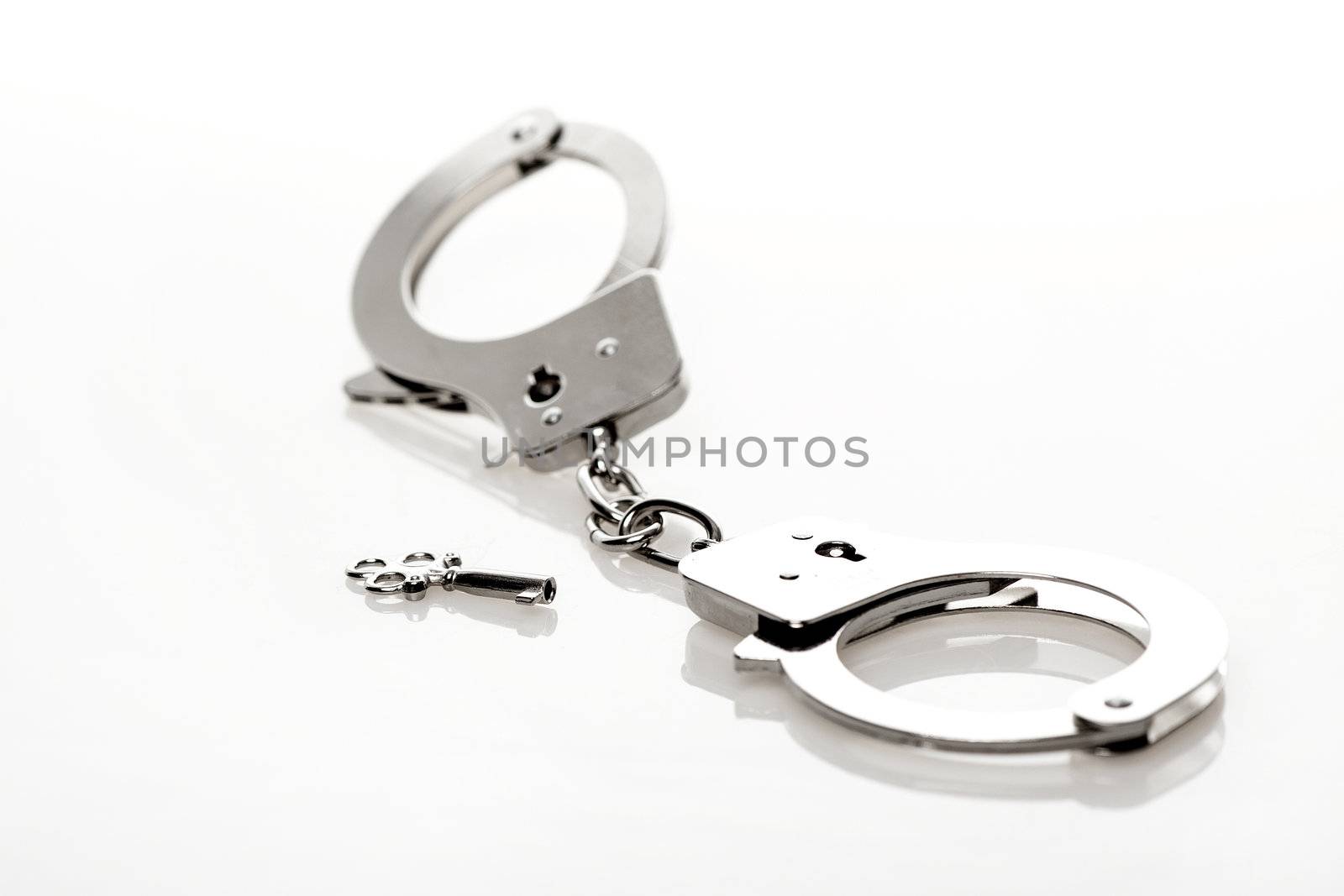 Handcuffs made of metal with a small key isolated on white