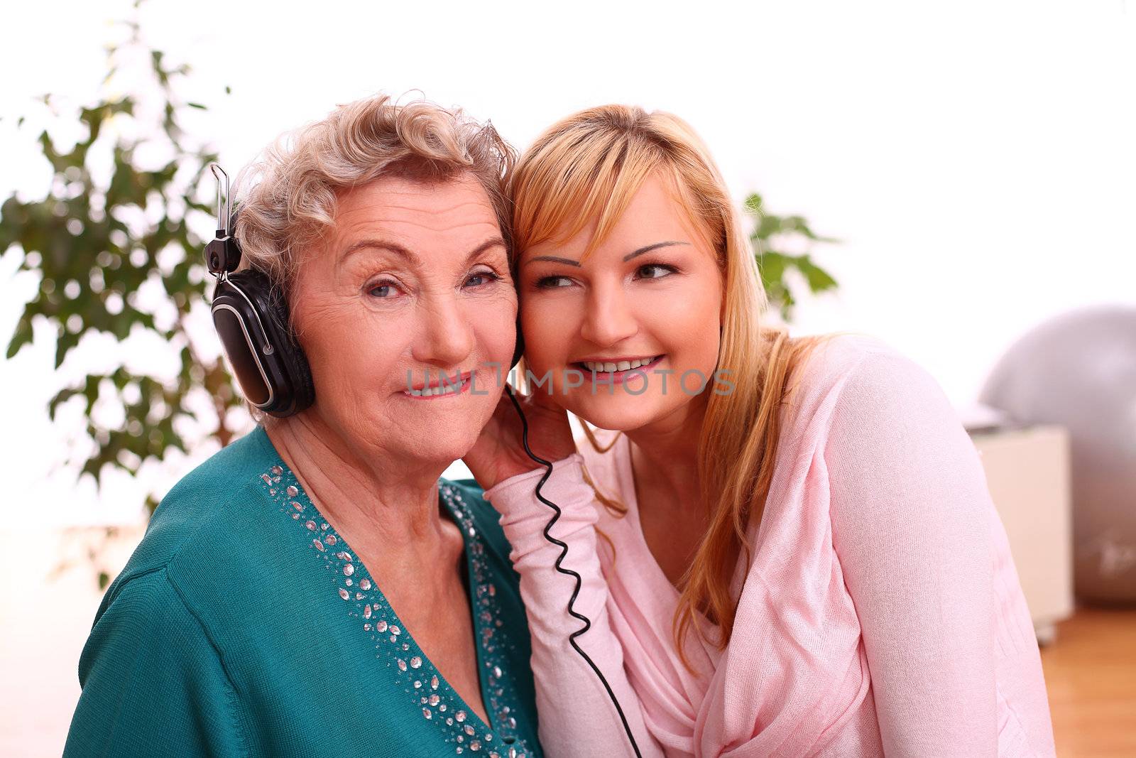 Happy elderly woman with granddaughter listening to the music at home