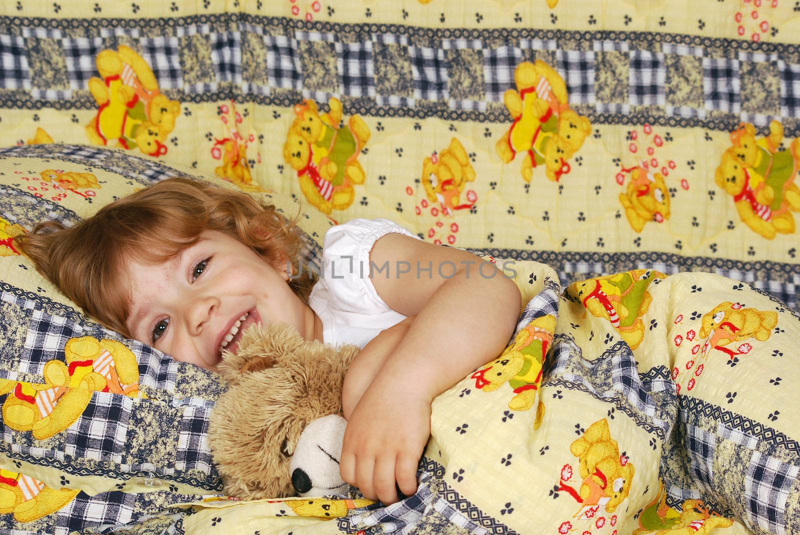 Little girl lying in bed with teddy-bear