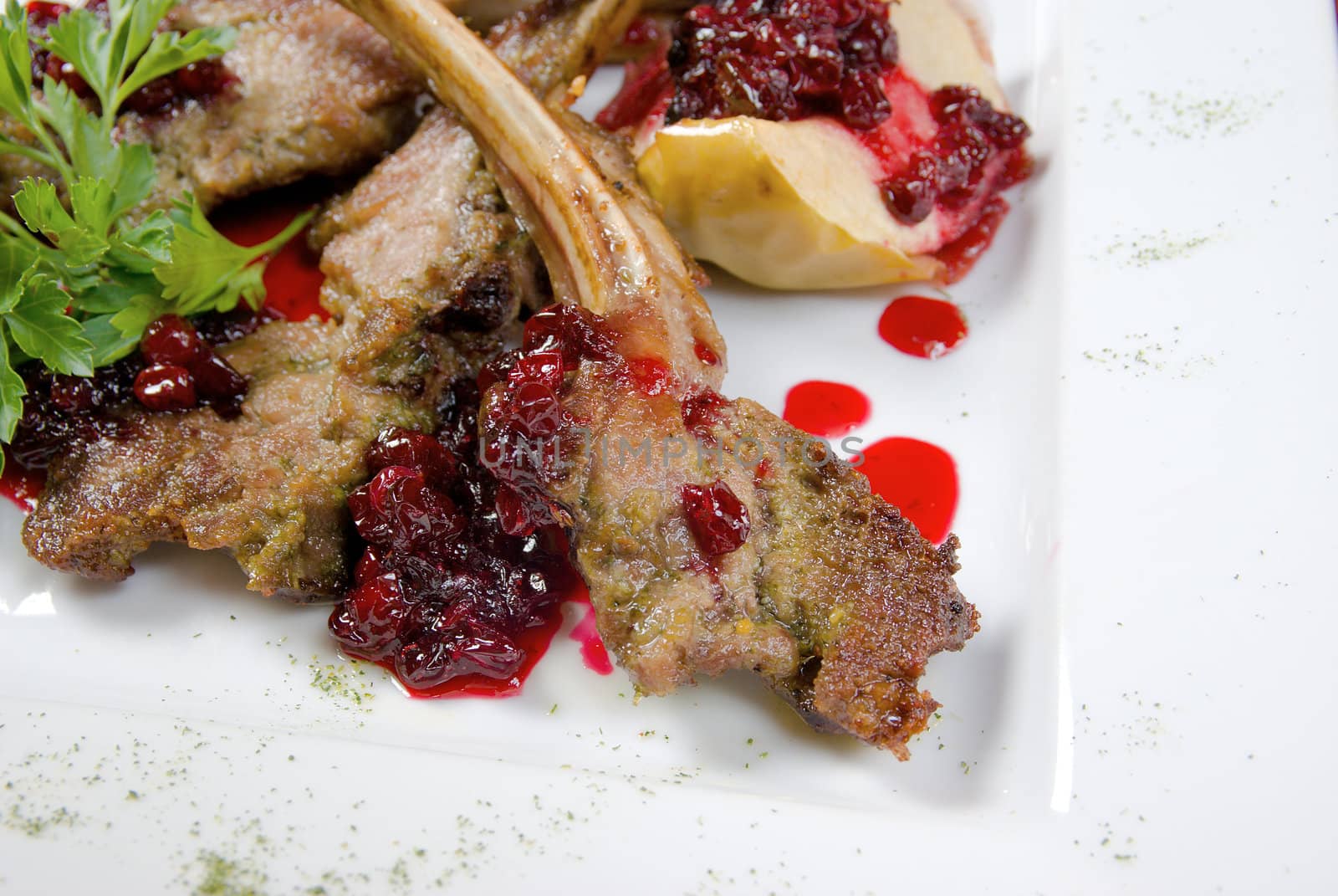 Italian kitchen.meat lamb on rib with cowberries by sauce