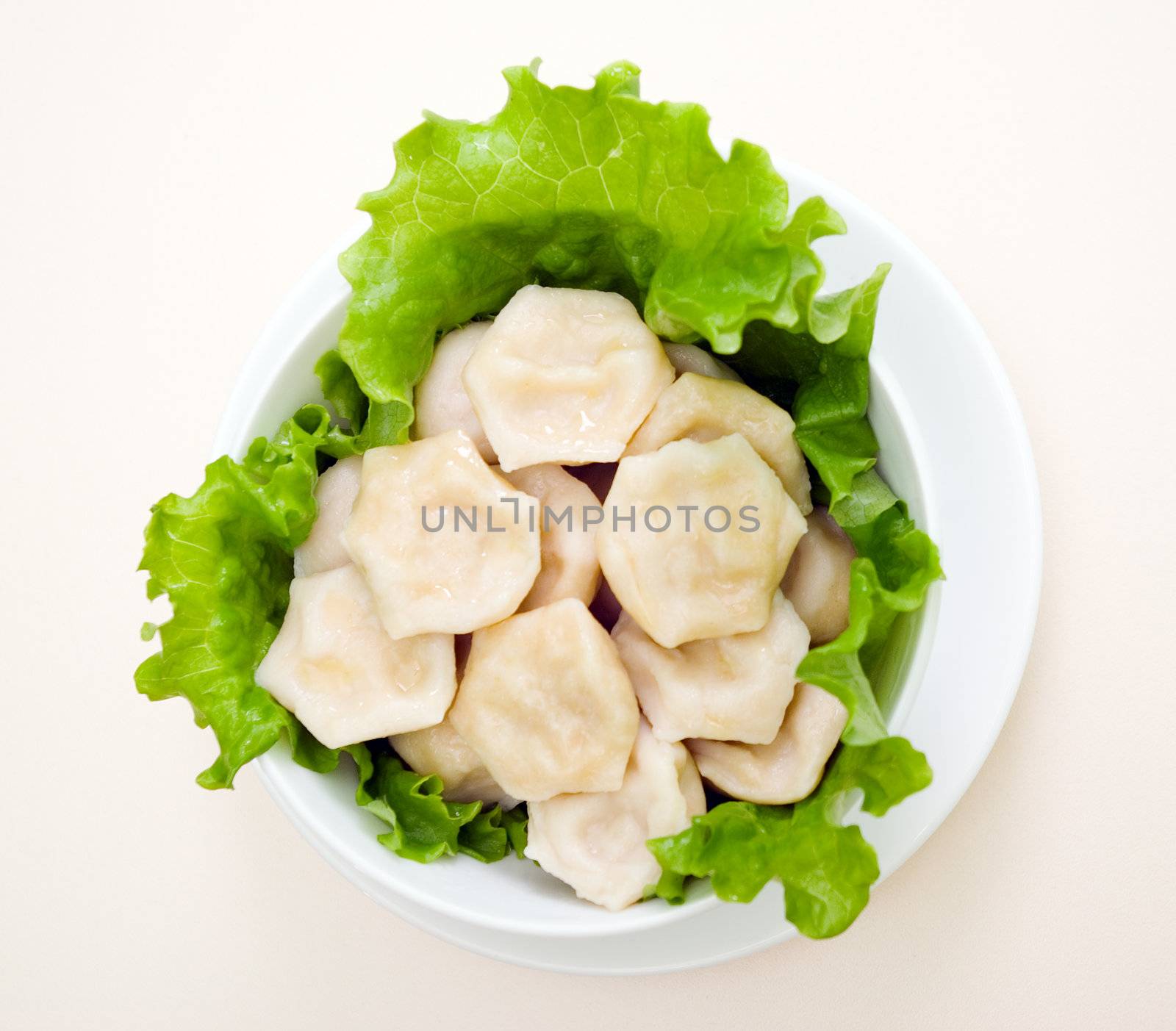Russian hot pelmeni in a dish, close up. with sheet of the salad