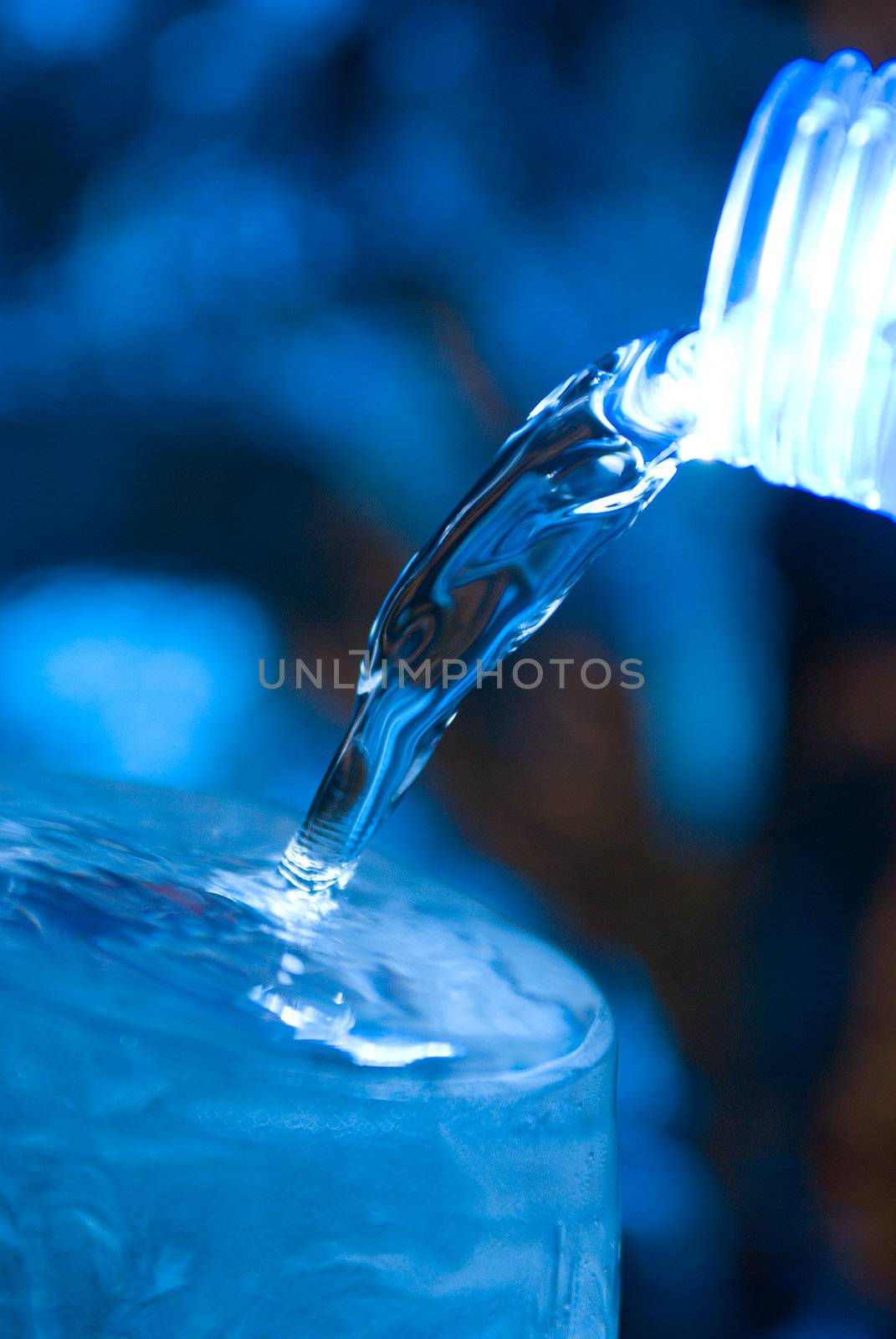 Bottle with creative splashing water.Macro of water poured into a glass of water 