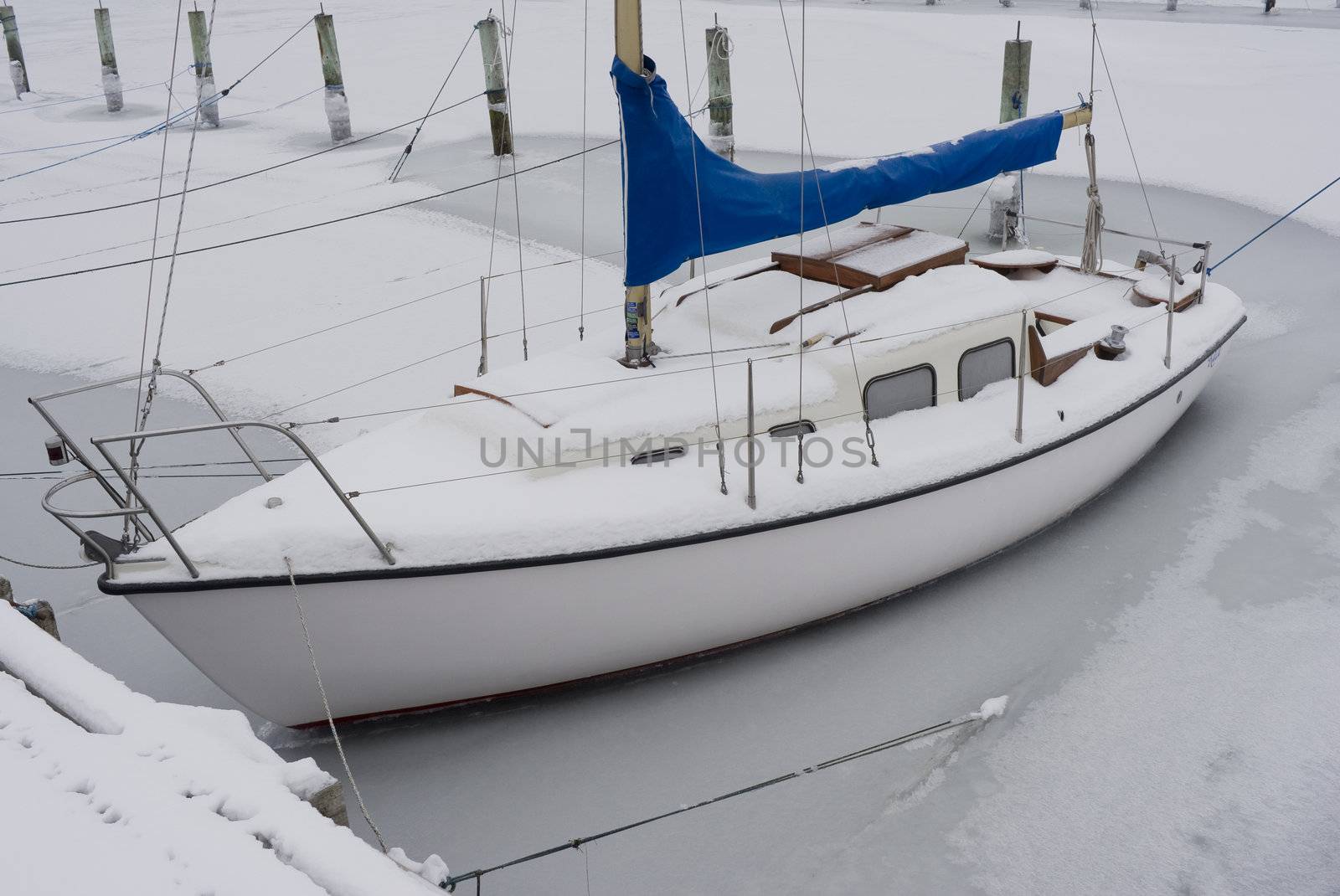 Icebound sailing boat in the marina of Nyborg, Denmark on a cold January day.