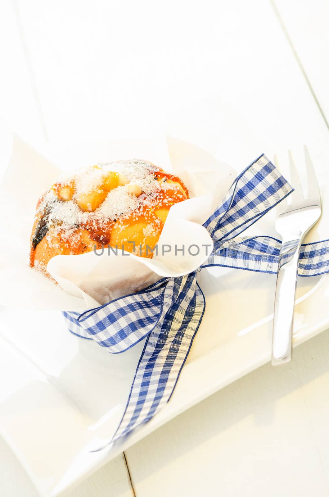 caramel muffin wrapped in baking paper and blue ribbon