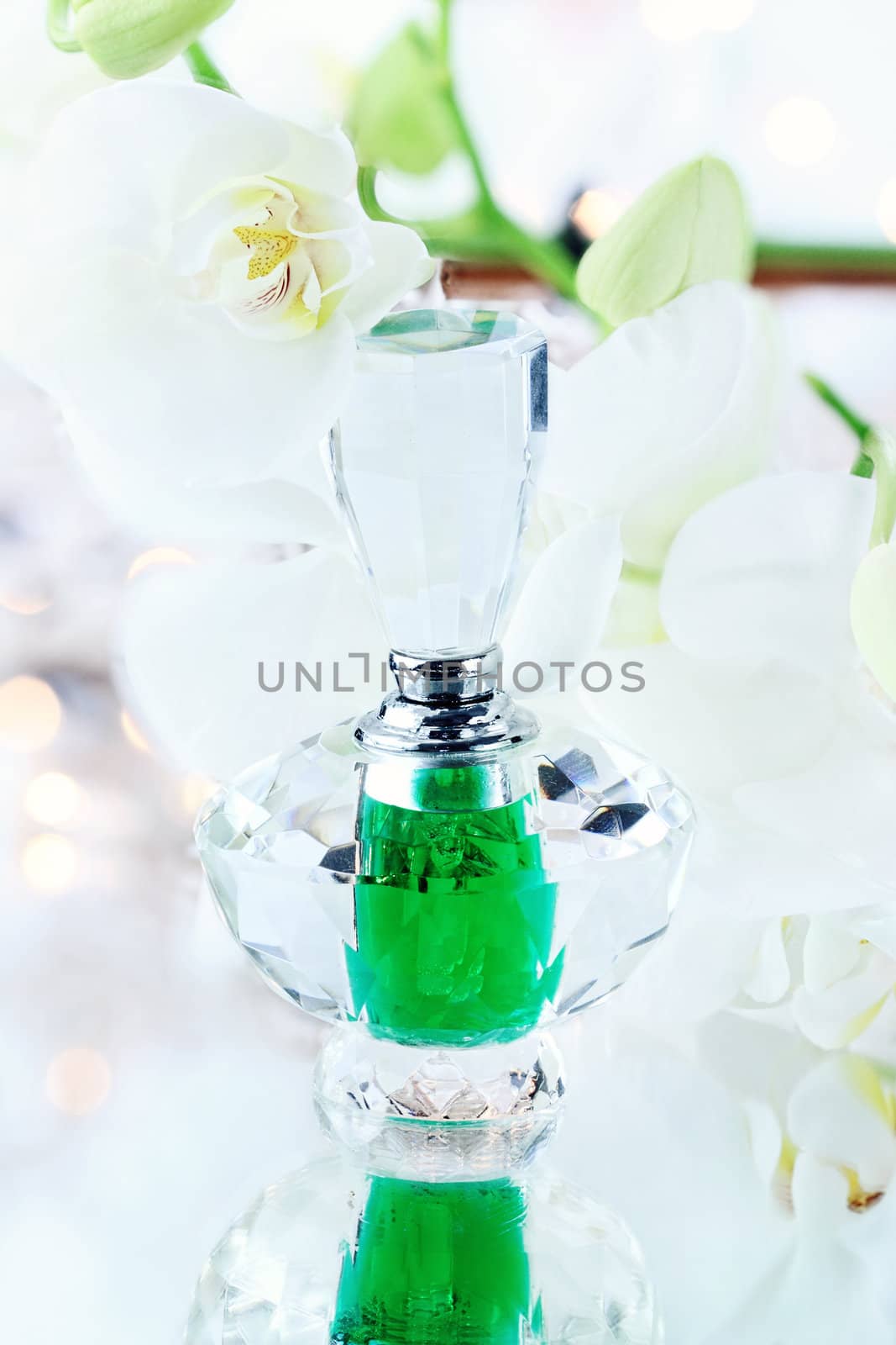 Beautiful bottle of perfume or essence with lovely white orchids.