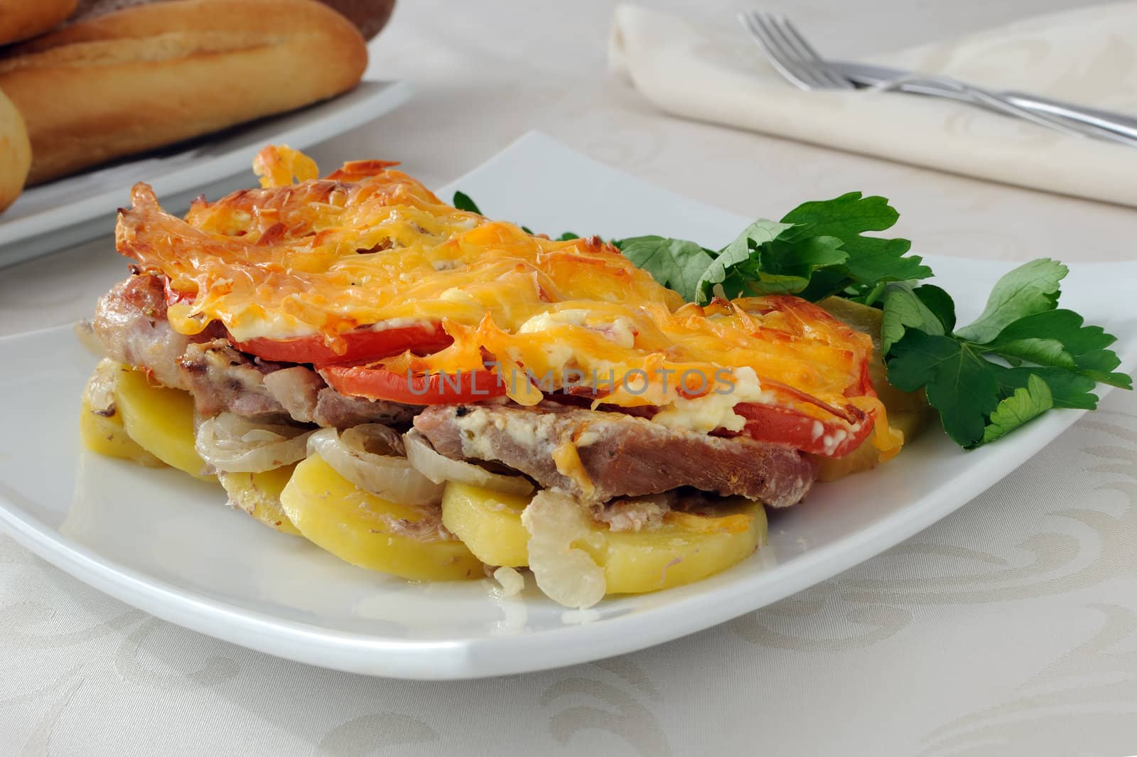 Baked potatoes with onions, meat and tomato with cheese