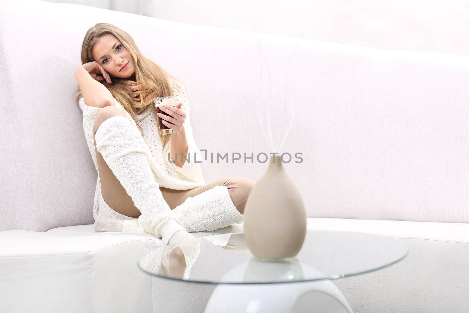 Long-haired blonde with a cup of coffee sitting on a sofa