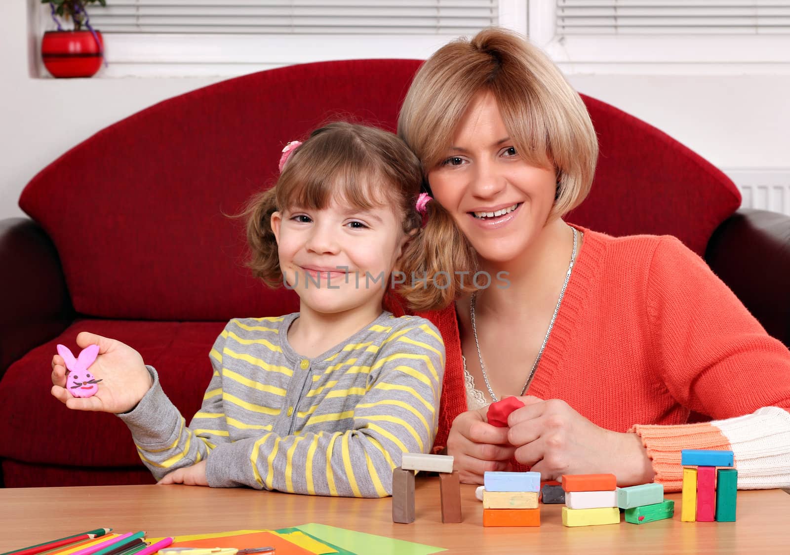 happy mother and daughter play with plasticine