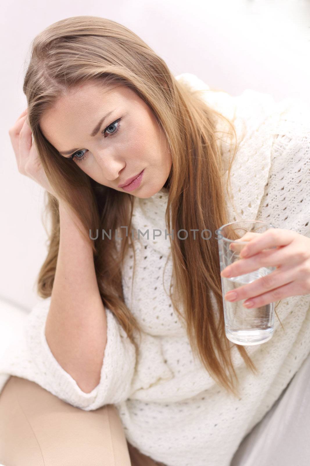 beige blonde glass hand long-haired pill sitting sofa water white young