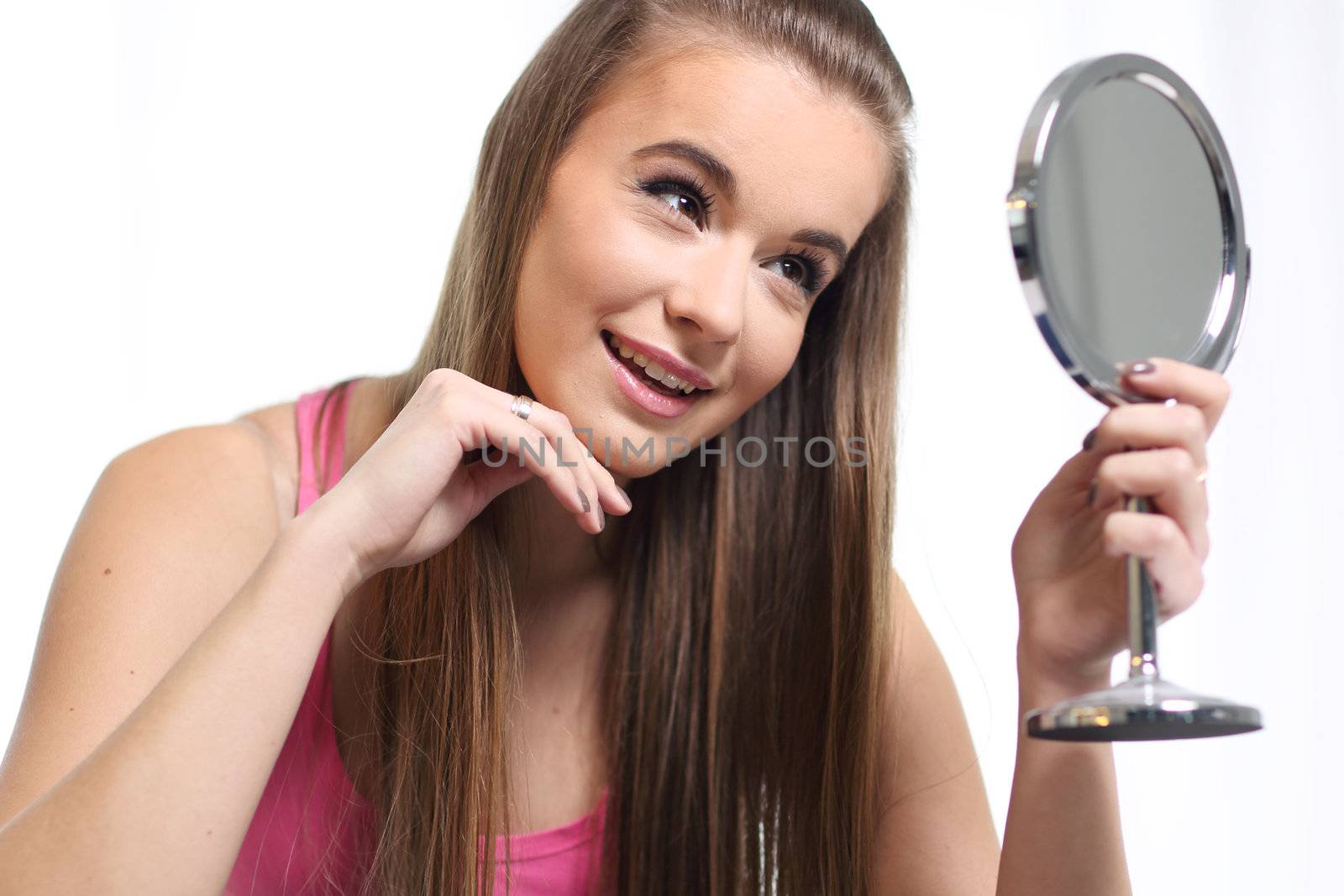 Young long-haired blonde sitting on the bed and looks at the mirror