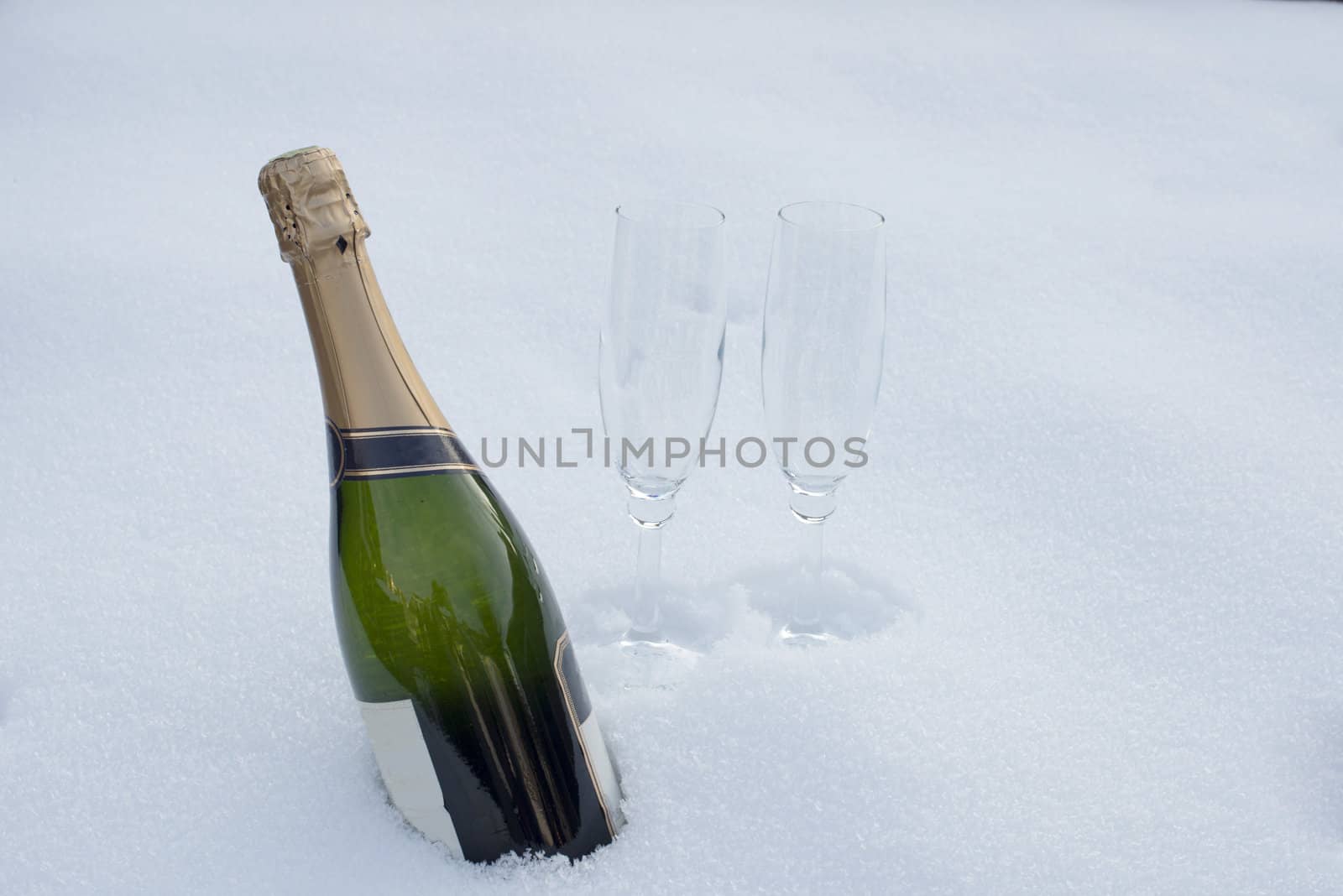 bottle of champagne and two glasses in the snow