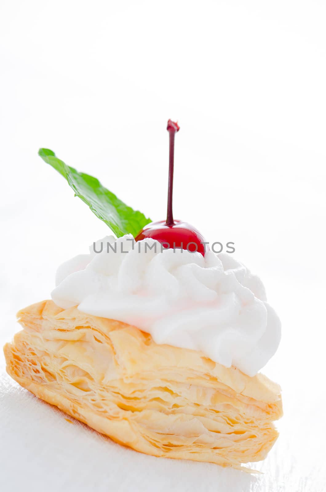 puff pastry cake with cream cherry and fresh mint leaf on white plate
