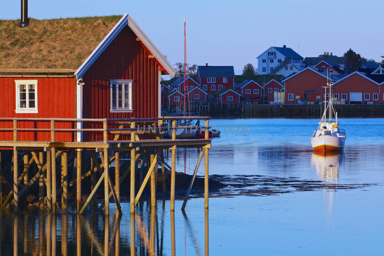 Typical red rorbu hut with sod roof lit by midnight sun in town of Reine on Lofoten islands in Norway