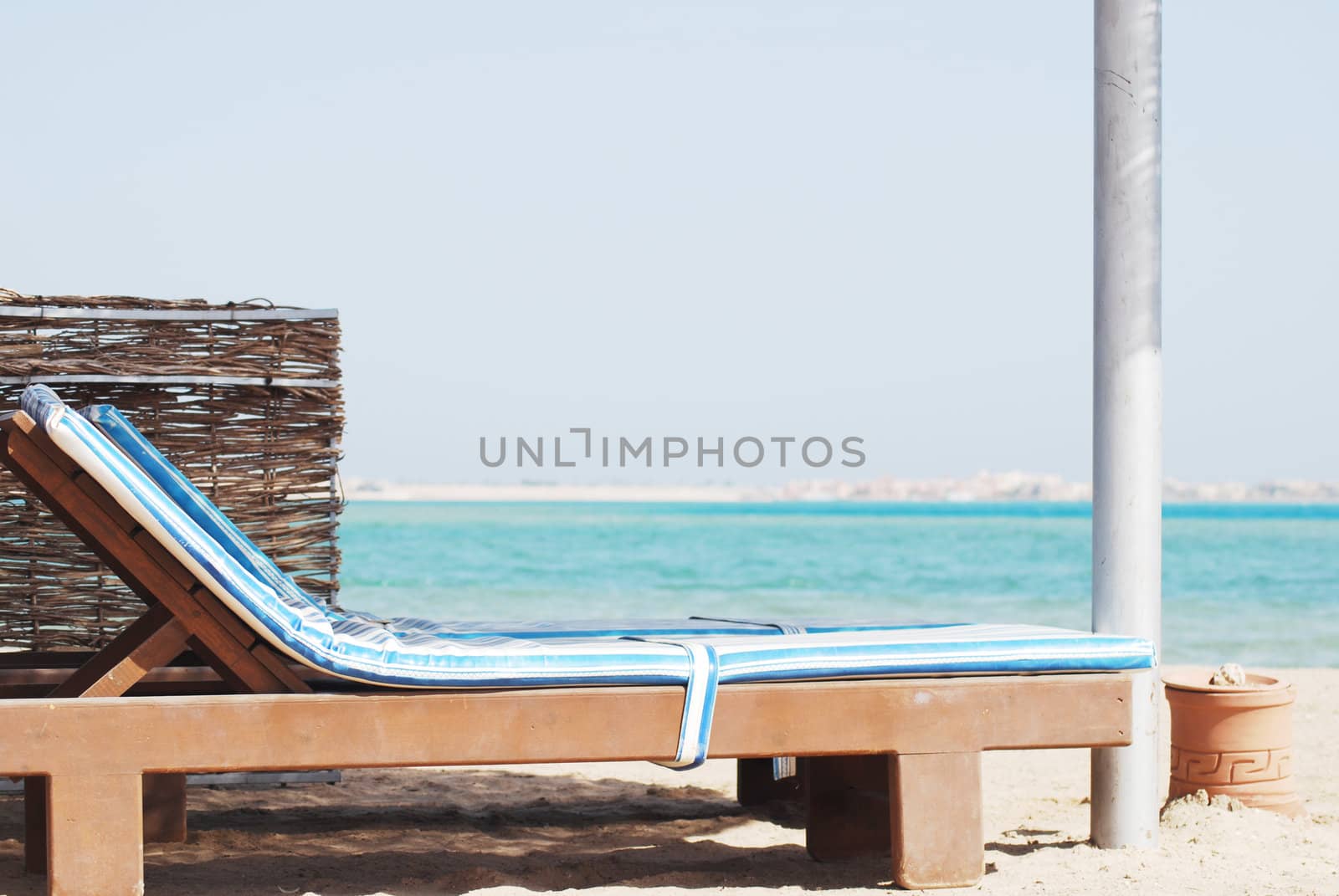 empty beach chair with straw sunshade at the sea