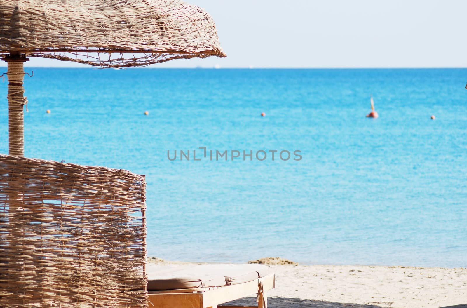 empty beach chair with straw sunshade at the sea by svtrotof