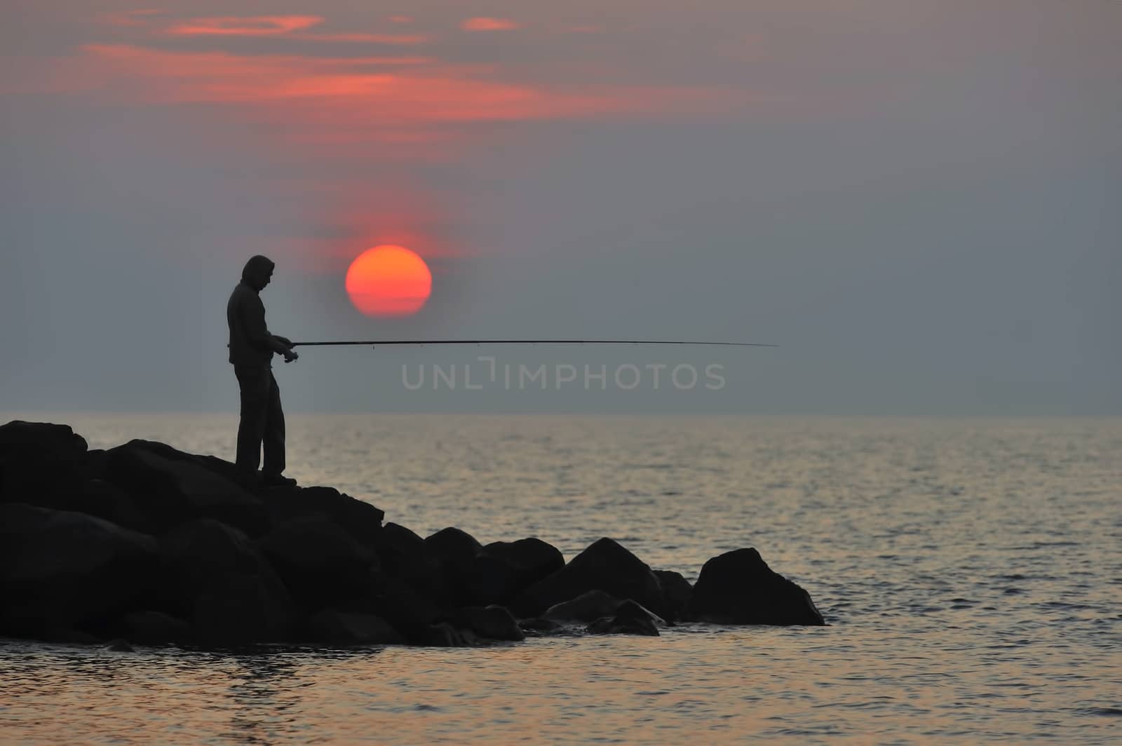 The fisherman at sunset is waiting for fish to bite