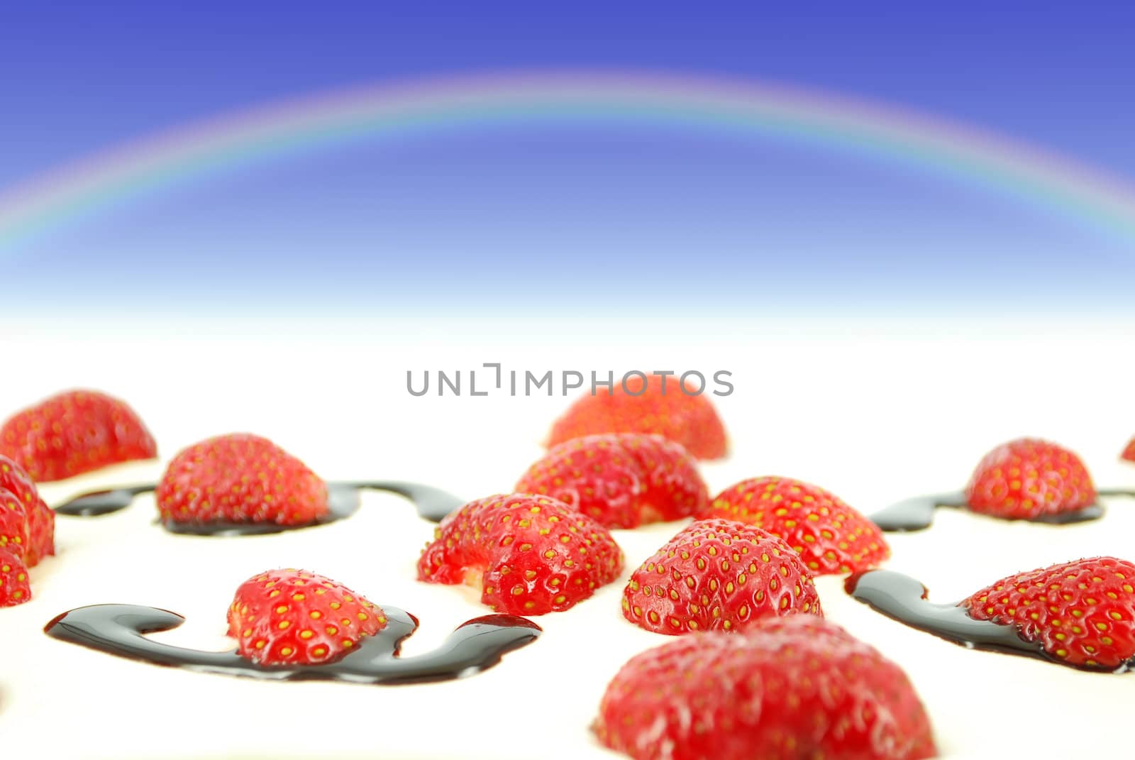 Sky with rainbow over red fresh strawberries