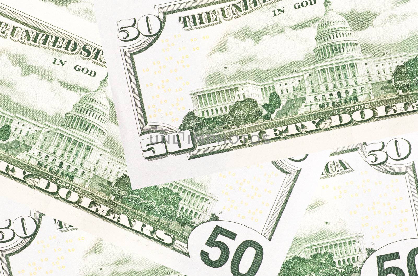 A stack of fifty 50 dollar bills fanned out with the back US Capitol showing on a white background