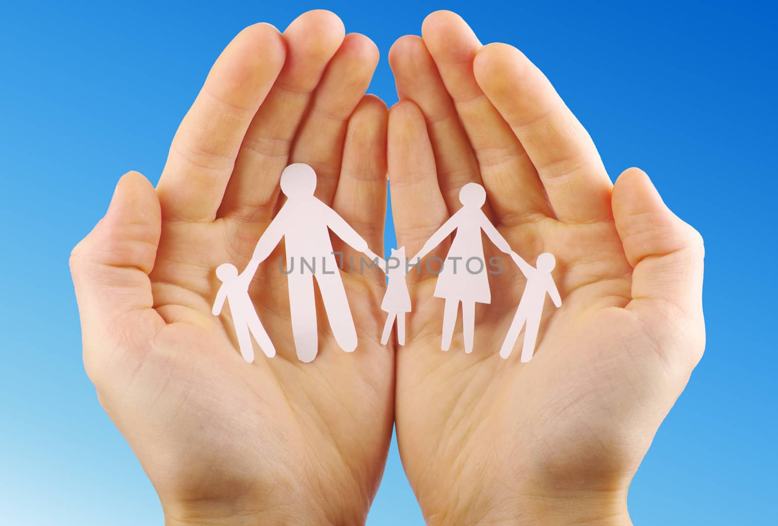 Paper family in hands isolated on blue sky
