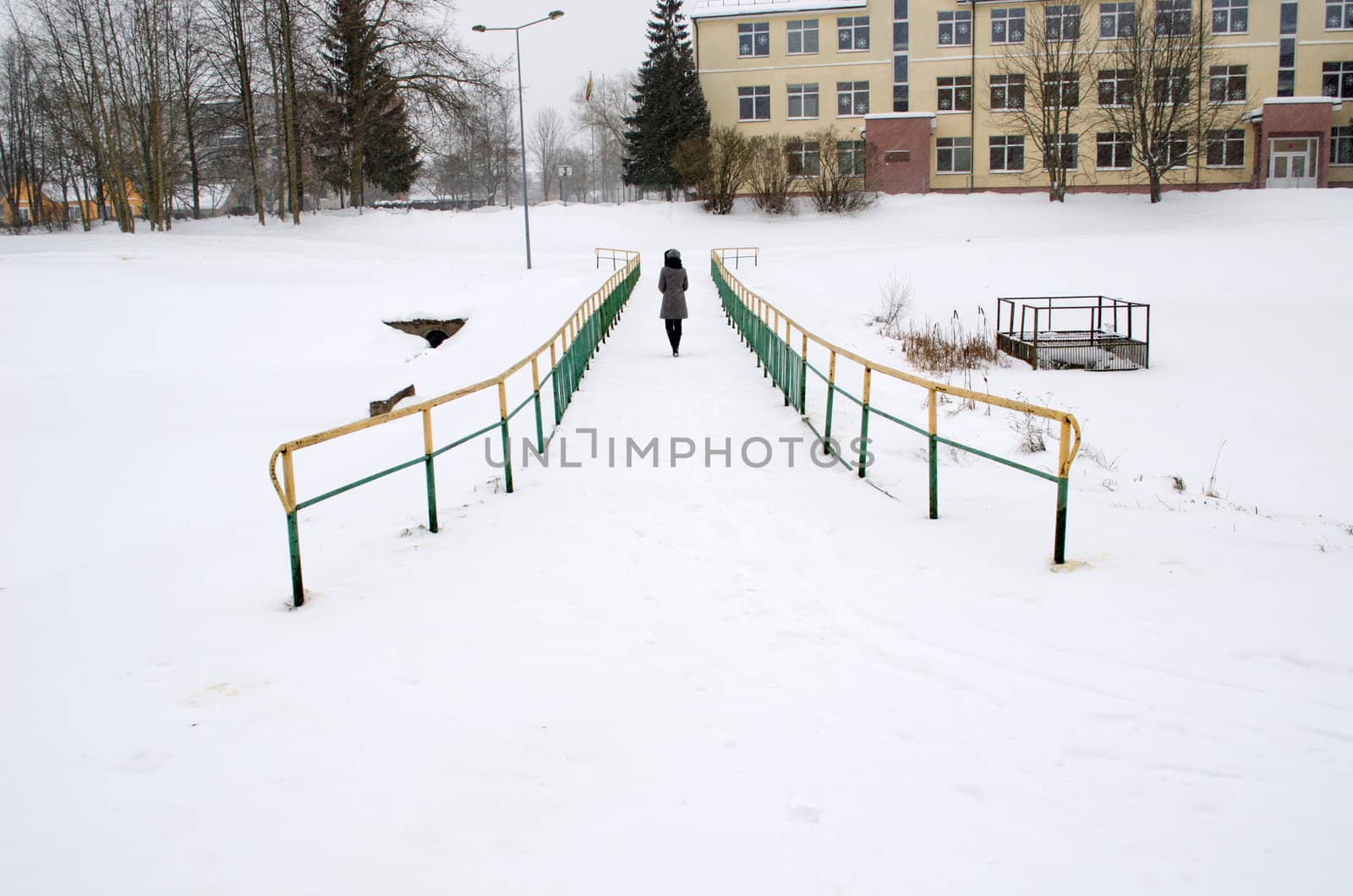 woman in grey coat walk through frozen river bridge in winter and snowstorm snow fall.