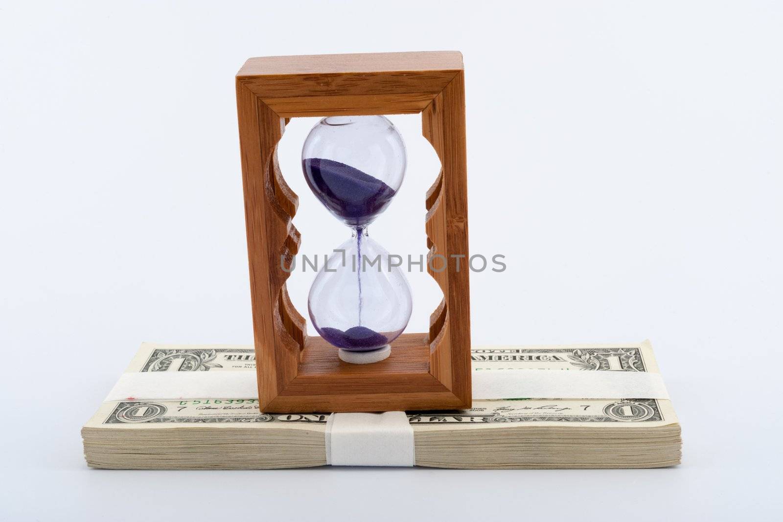 Hourglass on pile of paper money over  white background