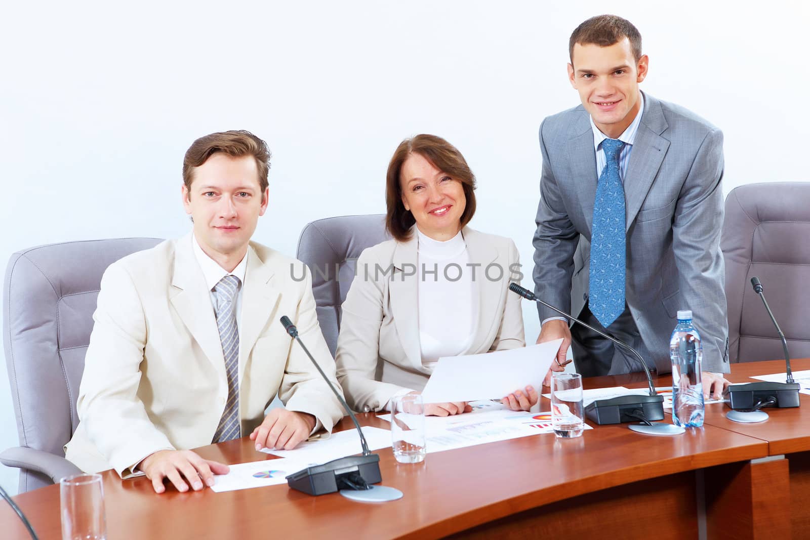 Image of three businesspeople sitting at table at conference