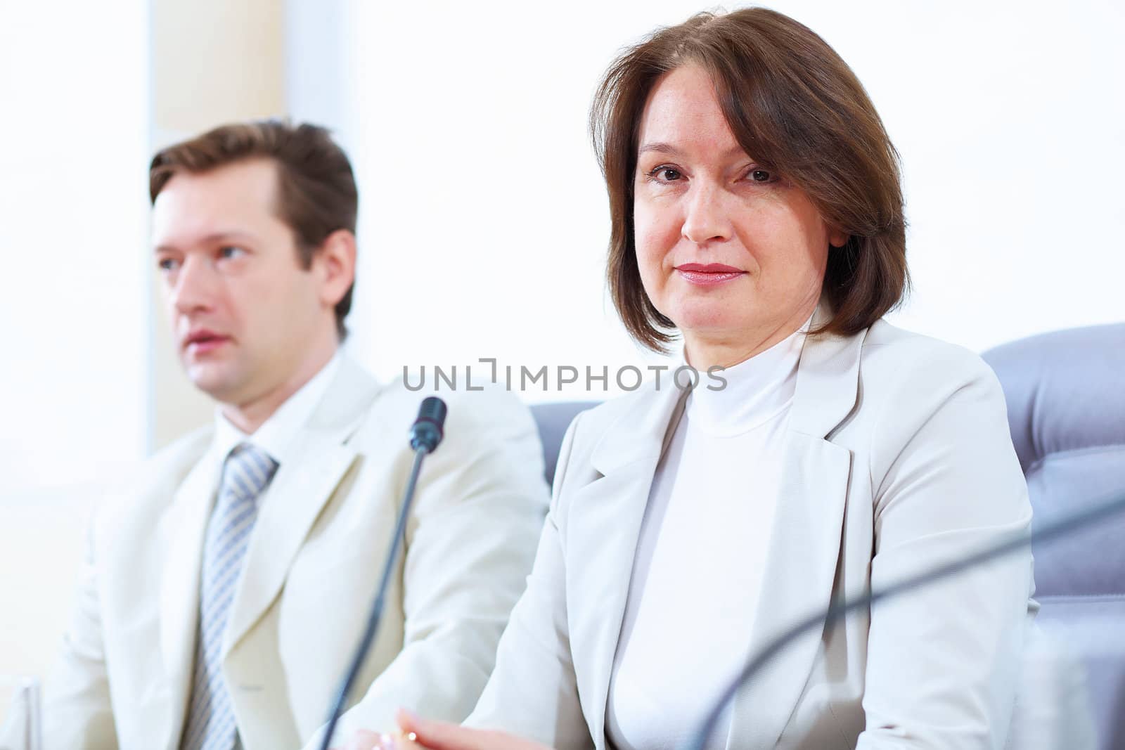 Image of two businesspeople sitting at table at conference