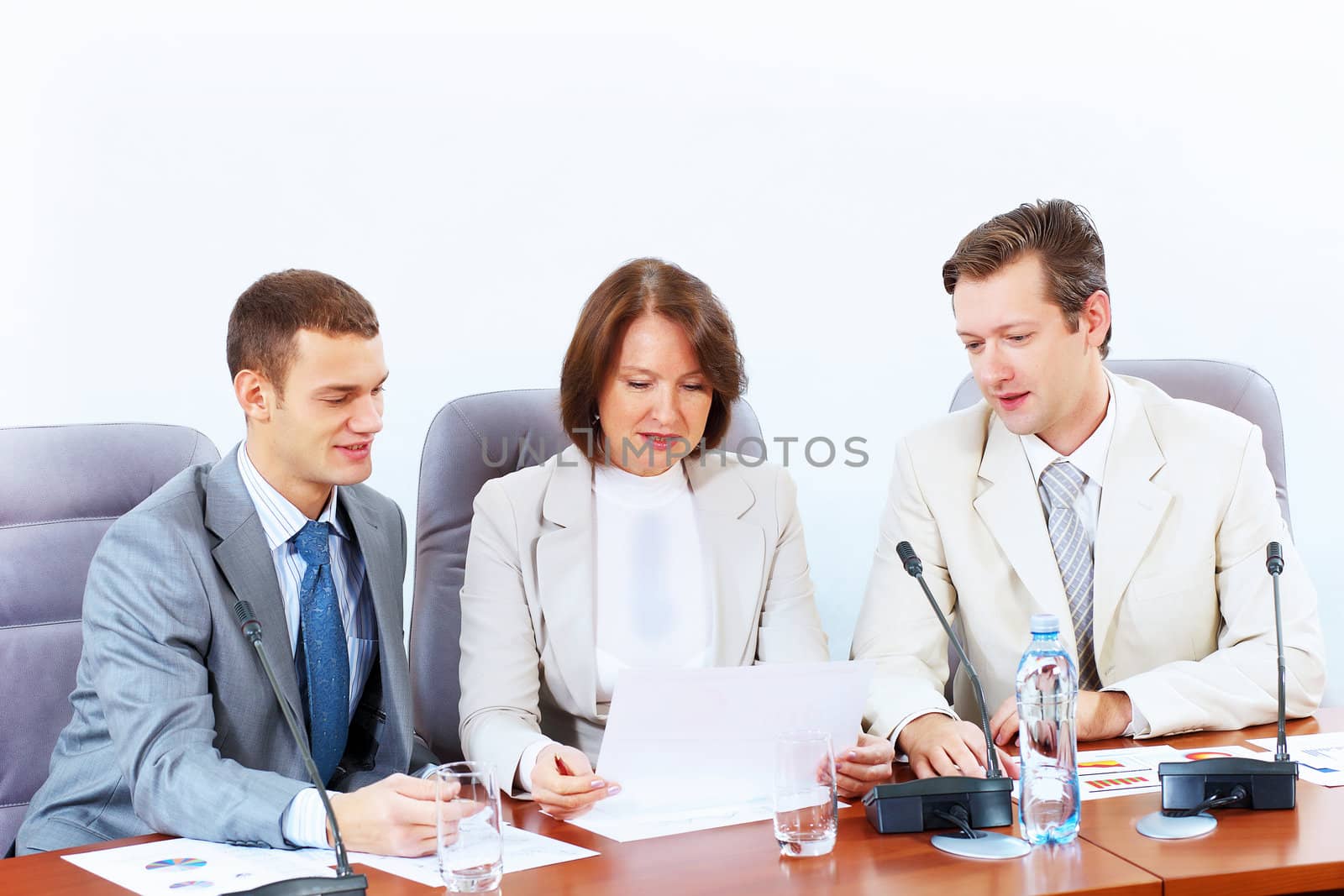 Image of three businesspeople sitting at table at conference