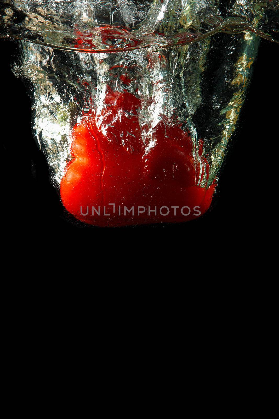 Colored red paprika in water splashes on black background