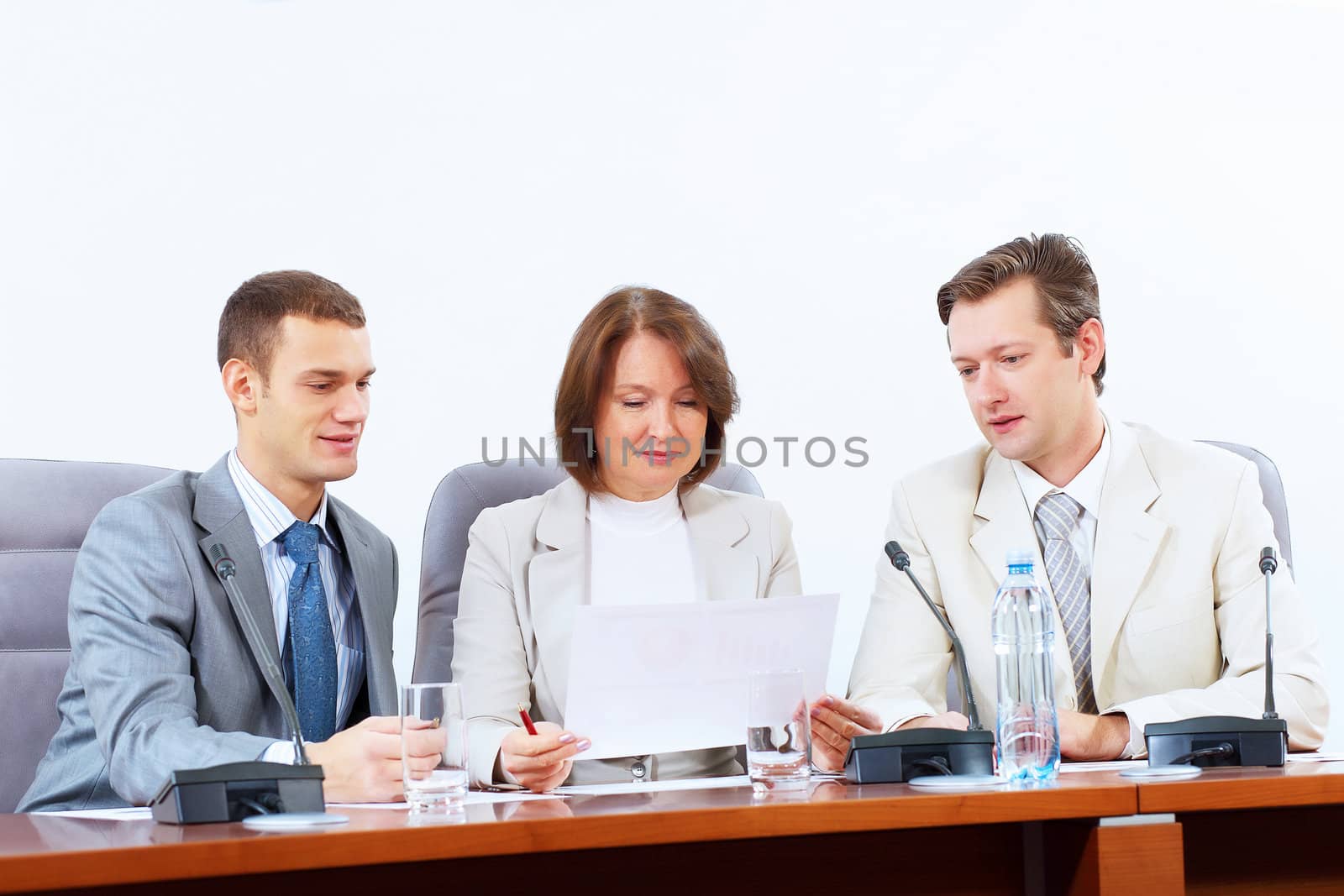 Image of three businesspeople sitting at table at conference