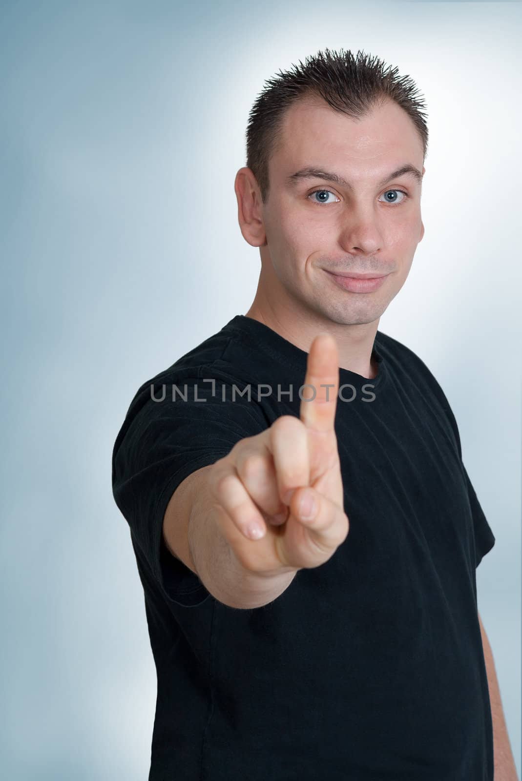 Portrait of a handsome young man pointing finger up 