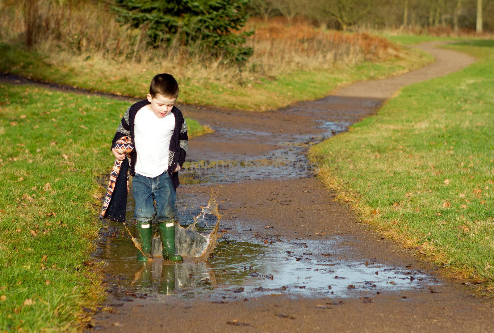 little boy splashing in a puddle