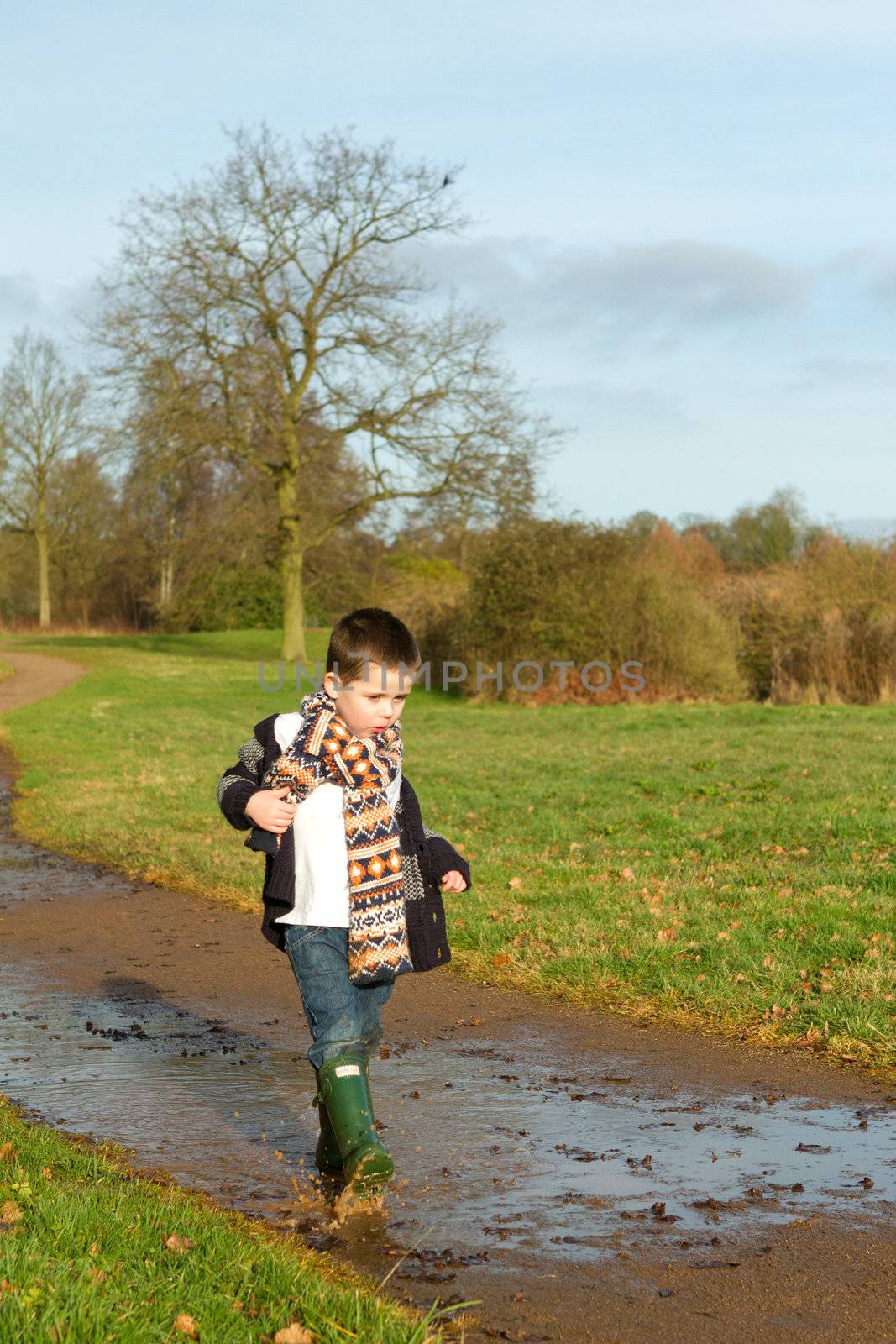 little boy splashing in a puddle