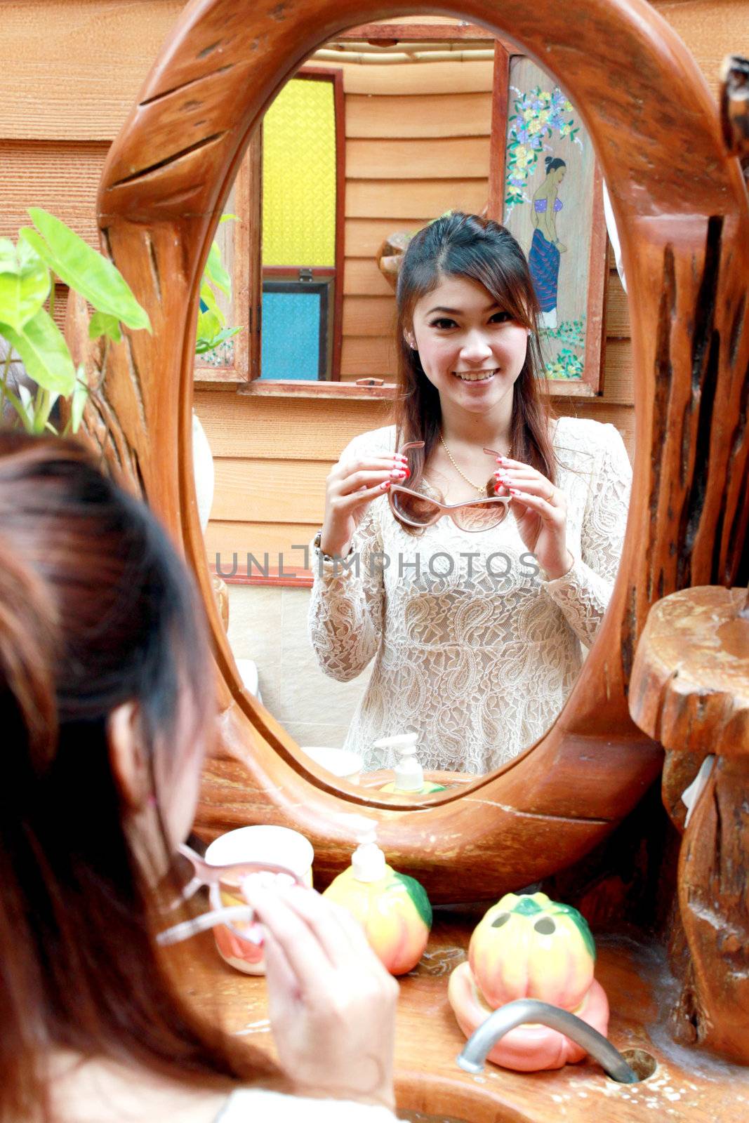 woman with glasses looking at herself in the mirror
