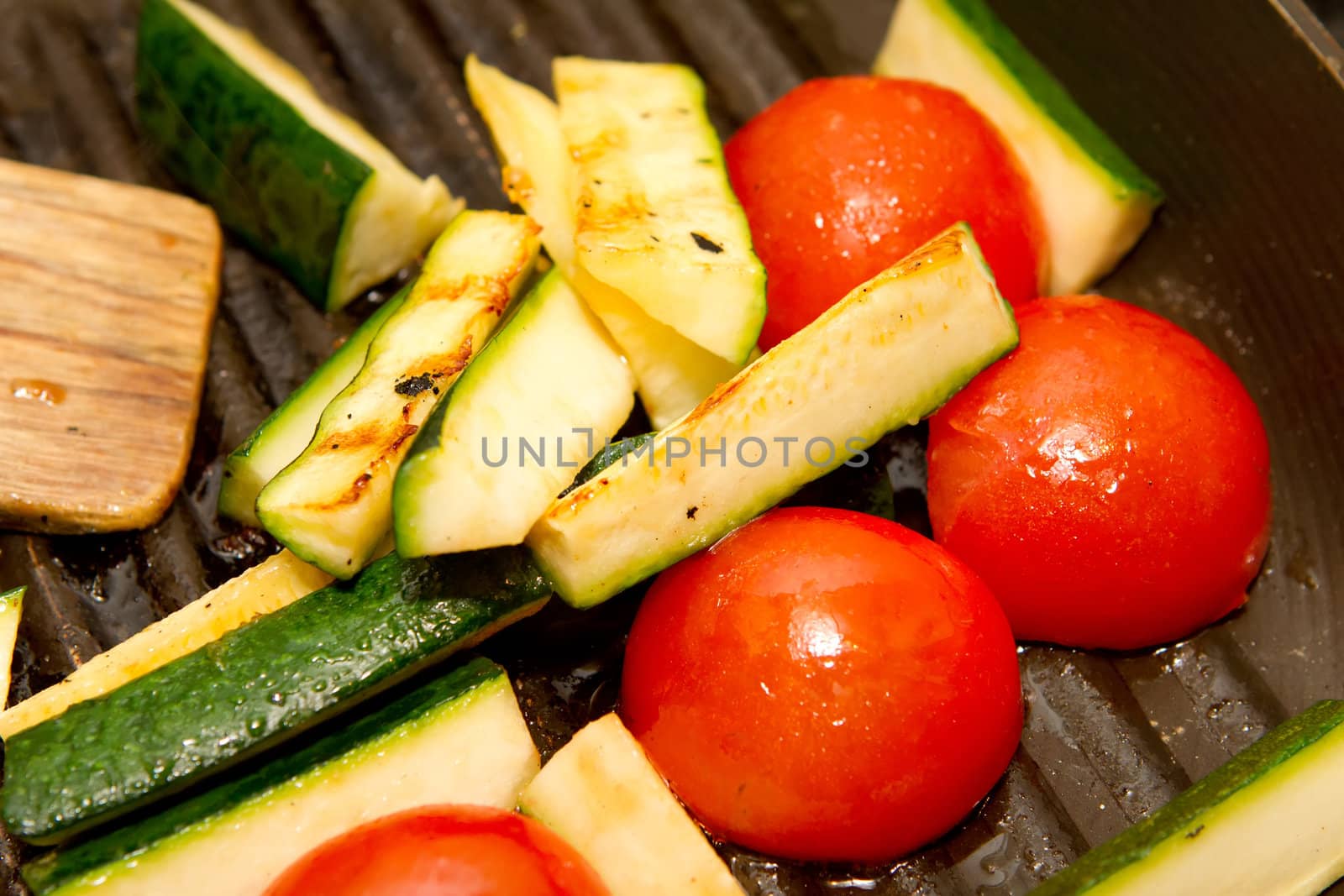 Corgettes and tomatoes frying in a griddle pan