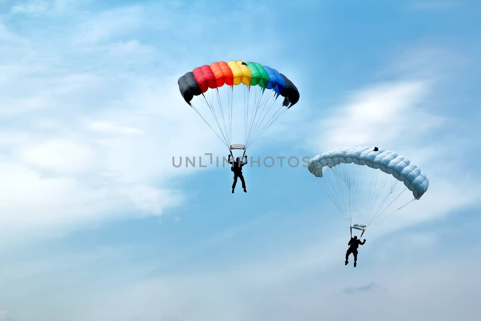 two silhouettes of unidentified skydivers on blue sky