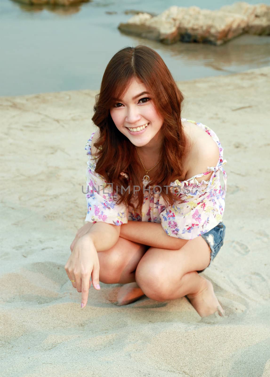 a portrait of beautiful woman on the sand with river
