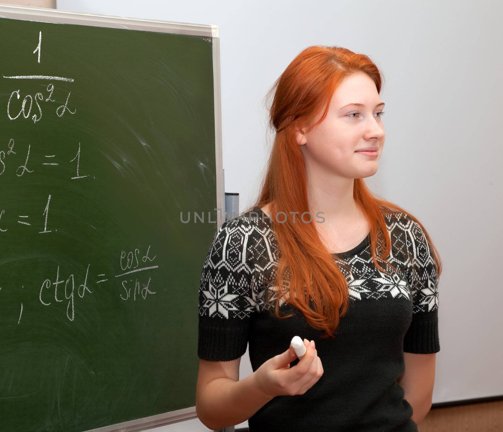 Girl in math class writing formulas on a blackboard
